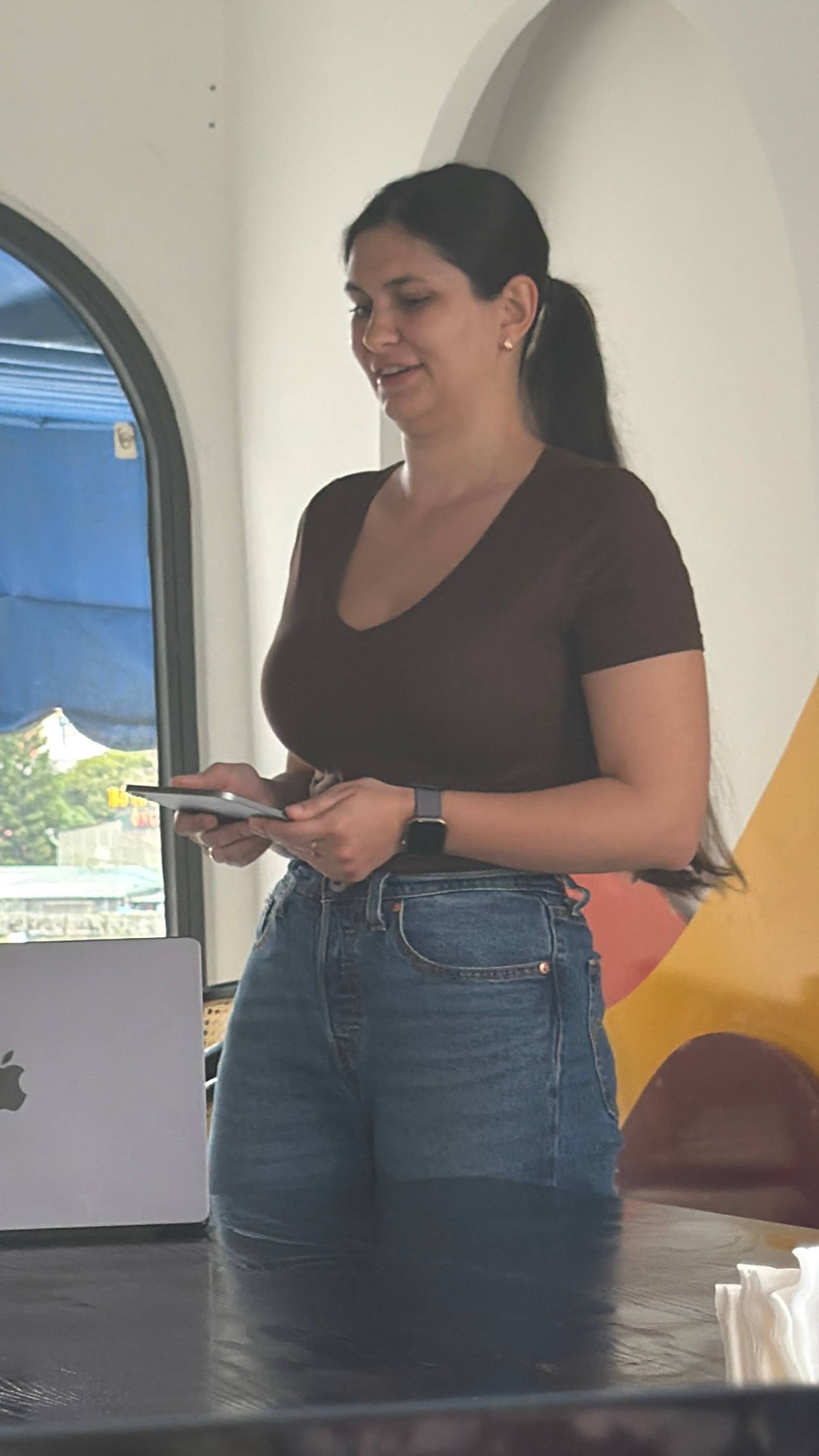 A participant holds a mobile device during a professional event at a modern Đà Lạt venue, standing in a bright interior space with contemporary design and scenic views.