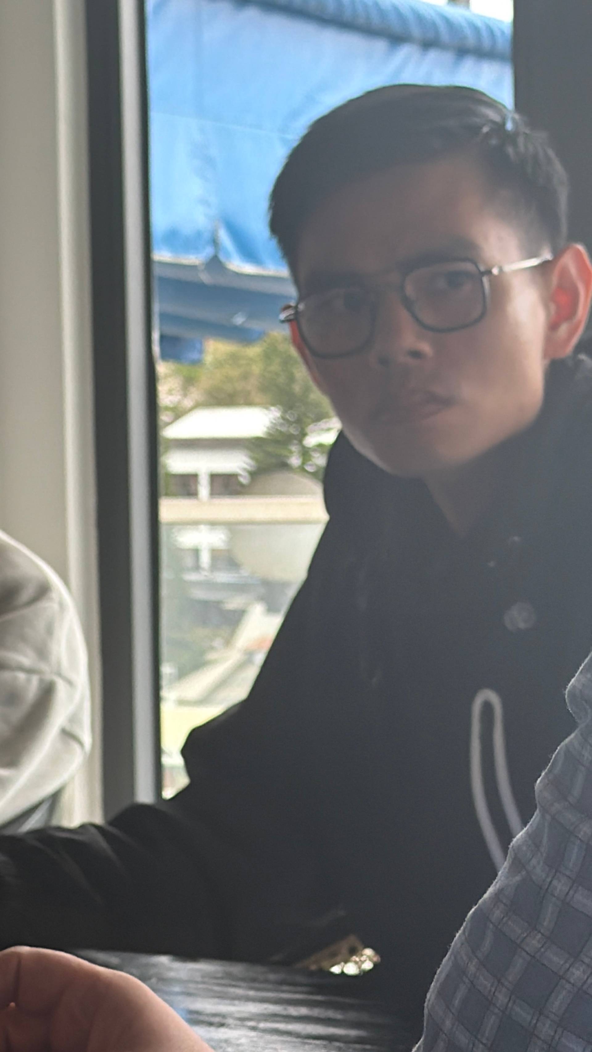 A participant pauses by a window during a professional event in a modern Đà Lạt venue, with scenic views visible in the bright contemporary interior.