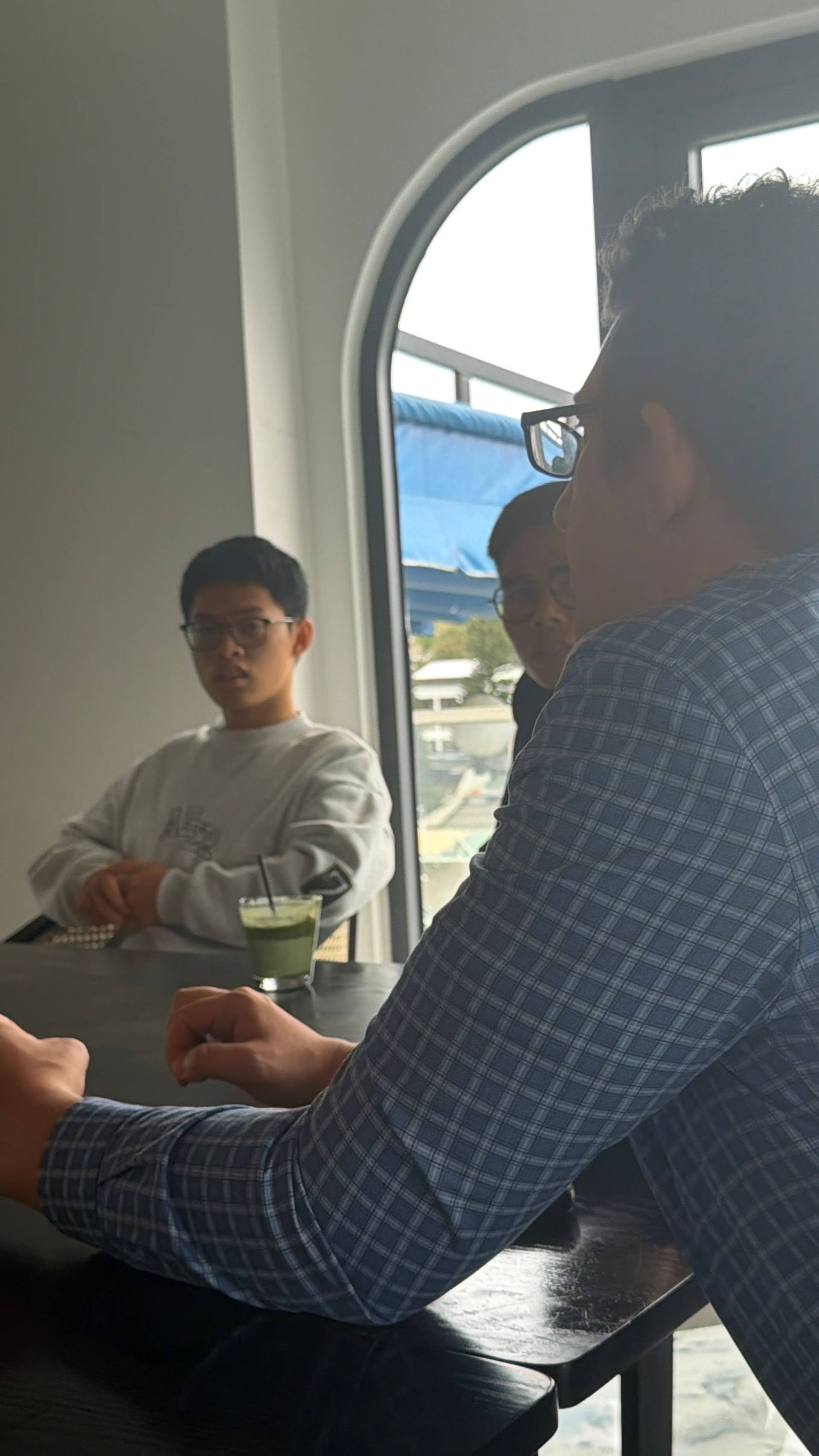A professional networking event unfolds in a modern Đà Lạt venue featuring contemporary art, designer lighting, and multiple participants engaged in collaborative discussion around workspace tables.