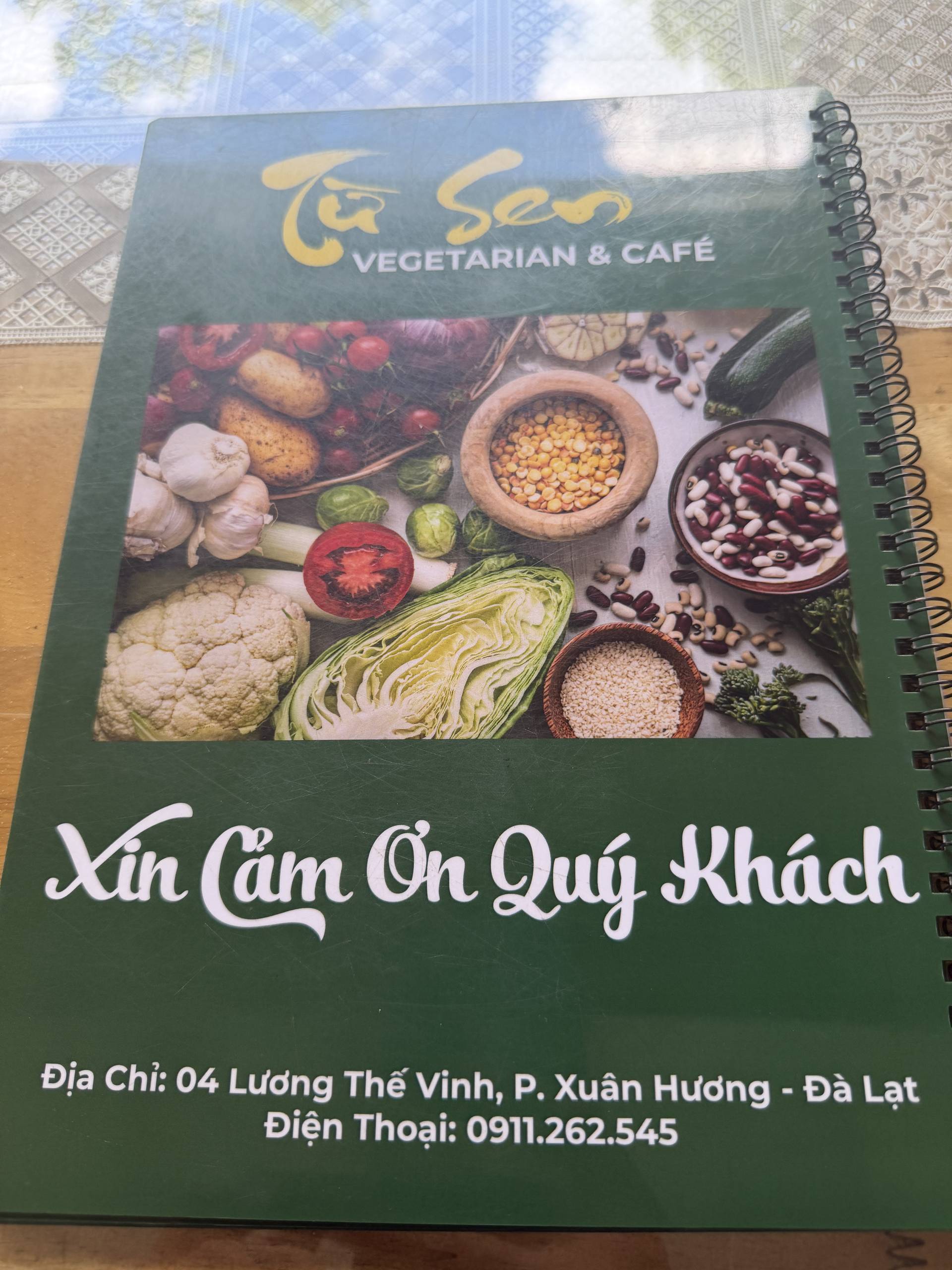 A menu from Tre Sen Vegetarian & Café in Đà Lạt's Xuân Hương district, featuring fresh produce imagery and Vietnamese hospitality messaging welcoming guests.