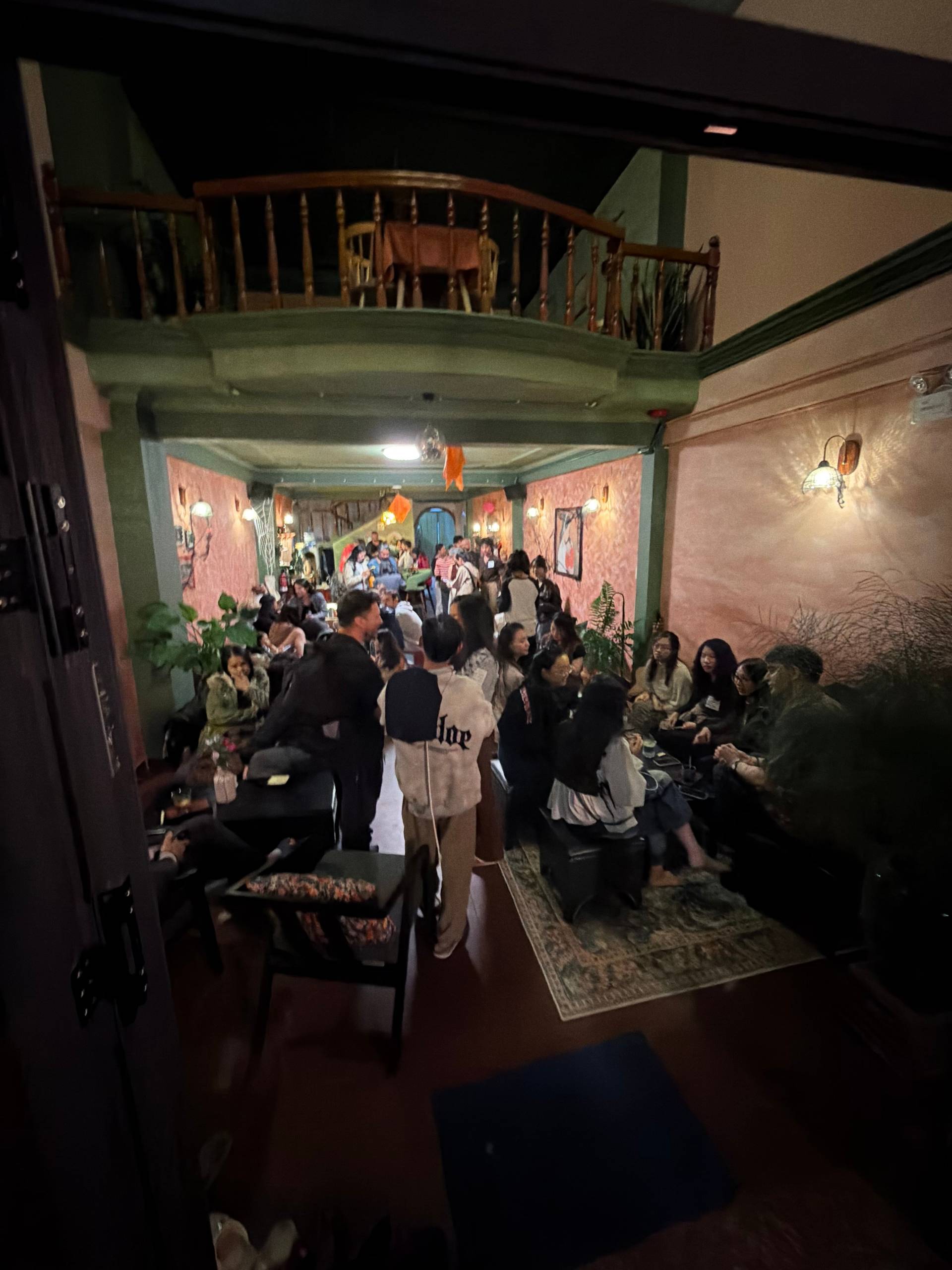 A lively gathering in a cozy, vintage-style café in Đà Lạt, Vietnam, with people enjoying drinks and conversations under warm lighting.
