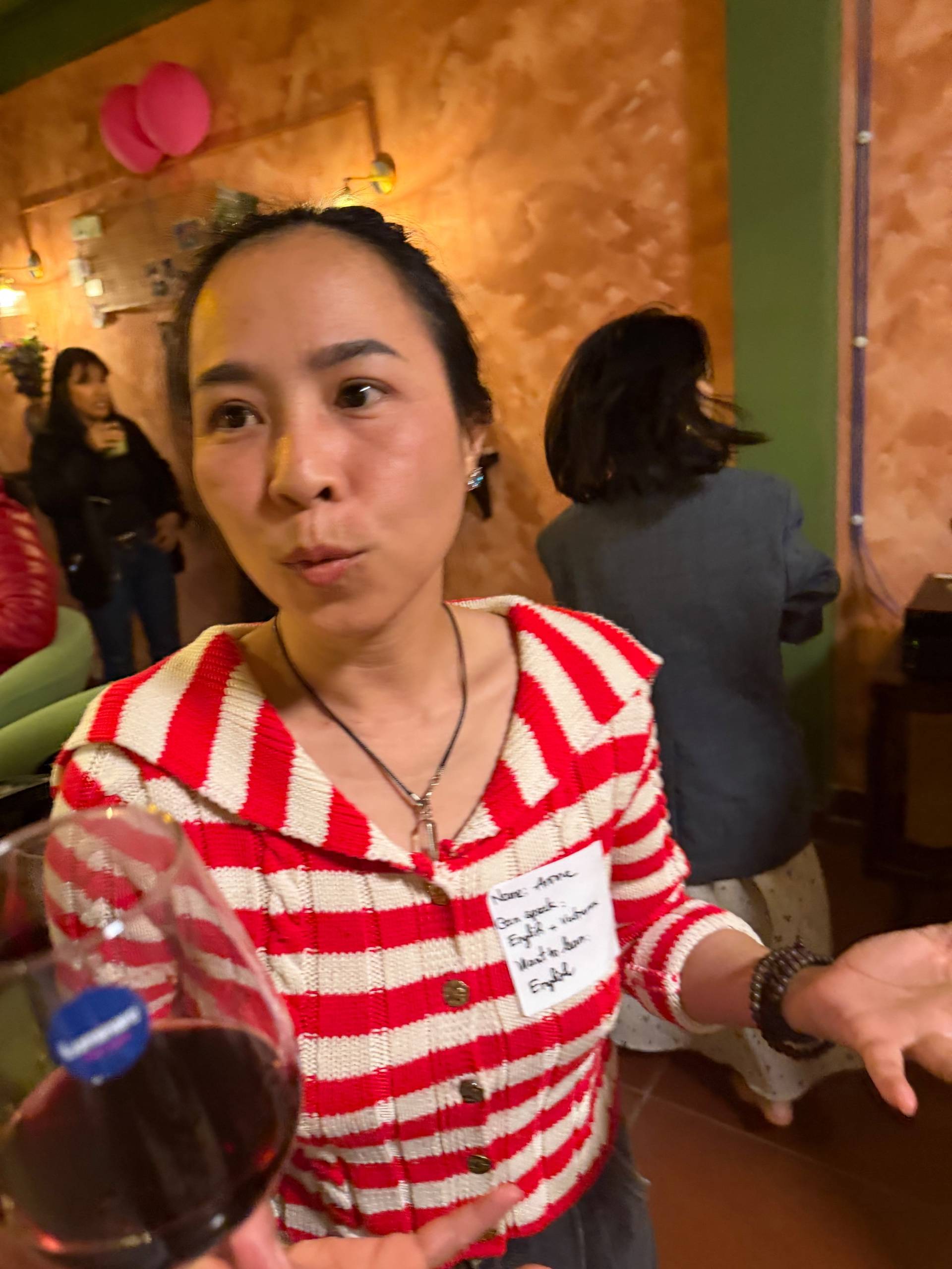 A lively gathering in Đà Lạt, Vietnam, with attendees enjoying drinks and engaging conversations in a cozy indoor setting.