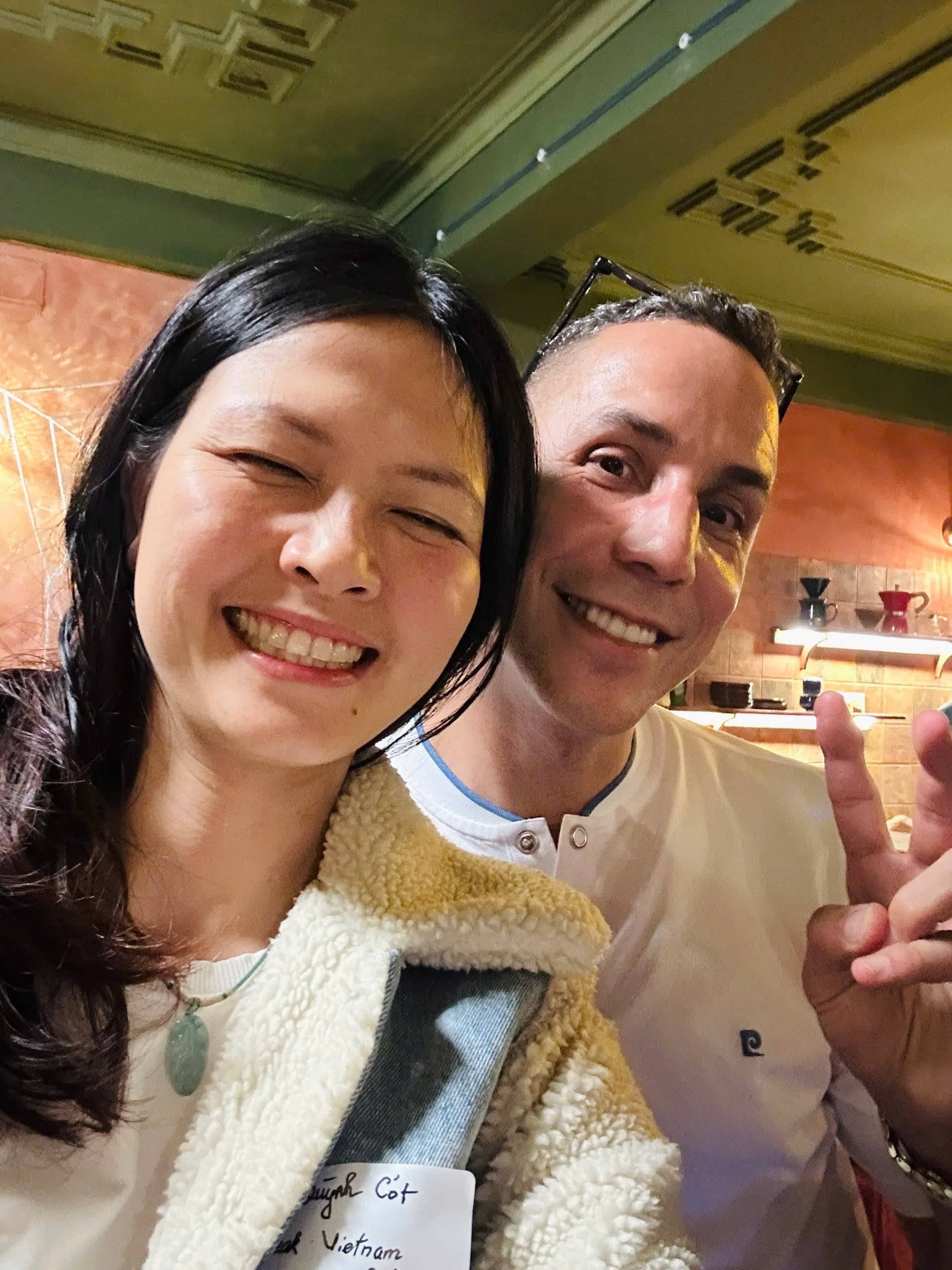Two individuals share a joyful moment in a cozy café setting in Đà Lạt, Vietnam, surrounded by warm lighting and rustic decor.