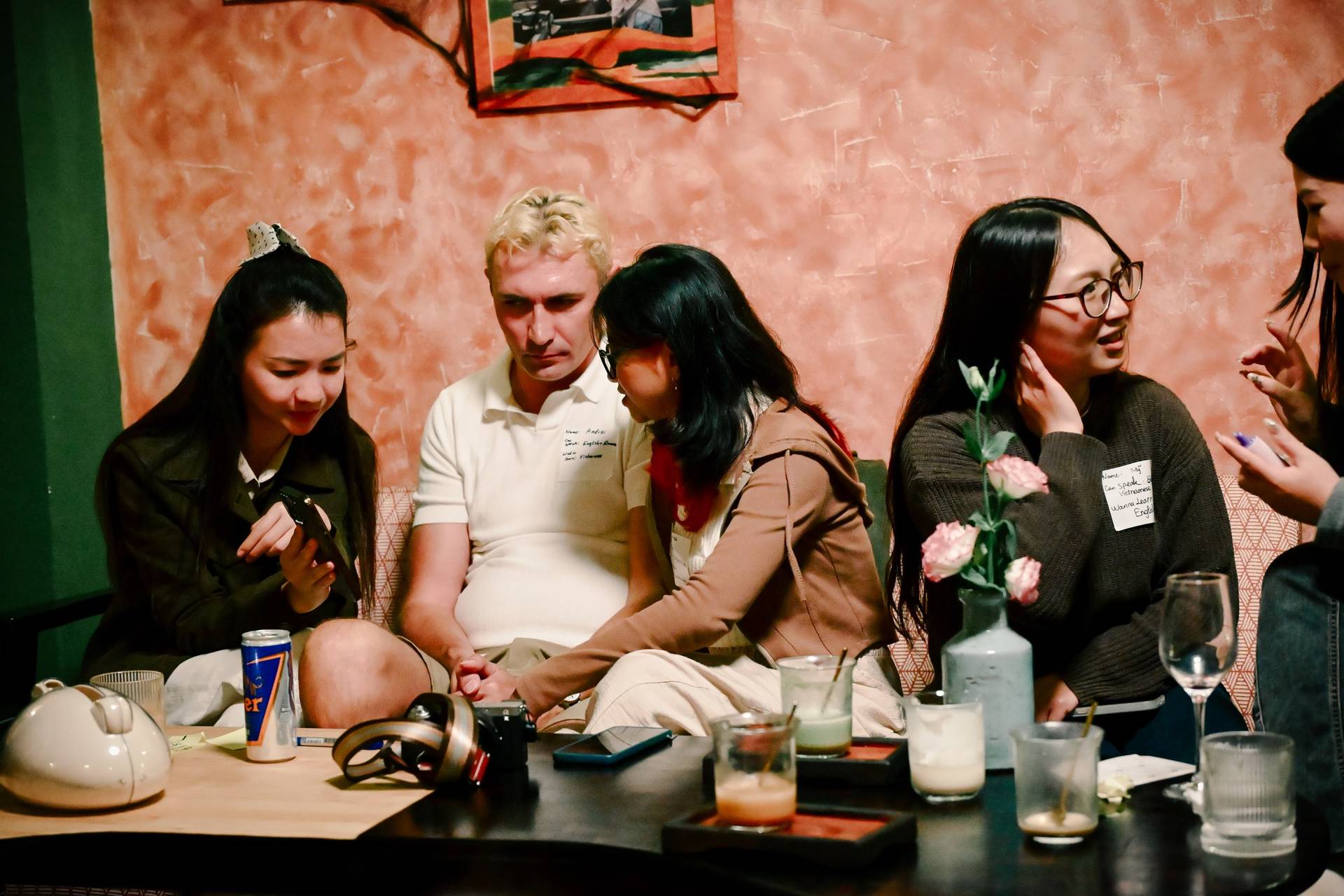 A group of friends gathered in a cozy café in Đà Lạt, Vietnam, engaging in lively conversation and enjoying drinks together.