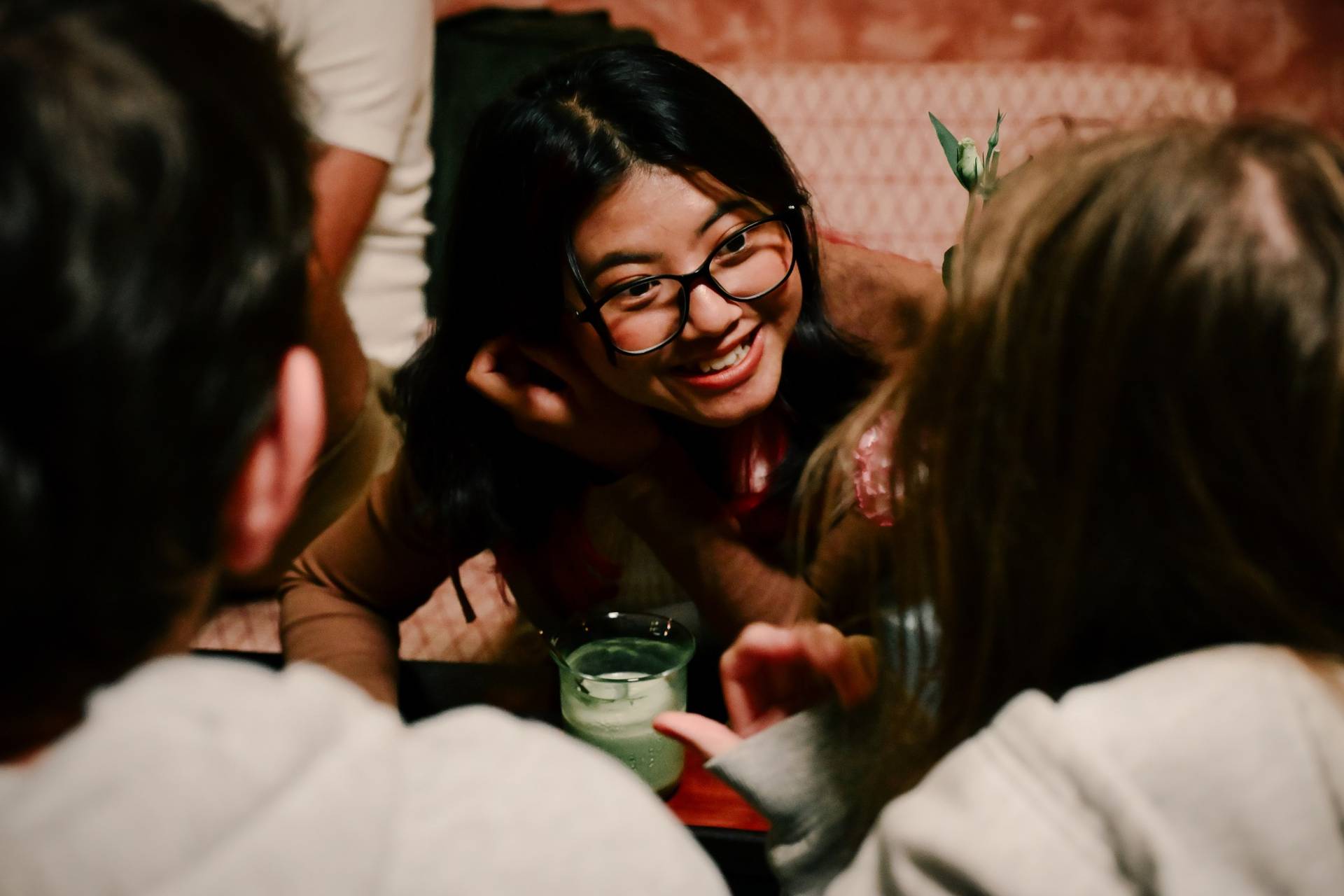A group of friends share a joyful moment in a cozy café setting in Đà Lạt, Vietnam, surrounded by warm lighting and intimate conversation.