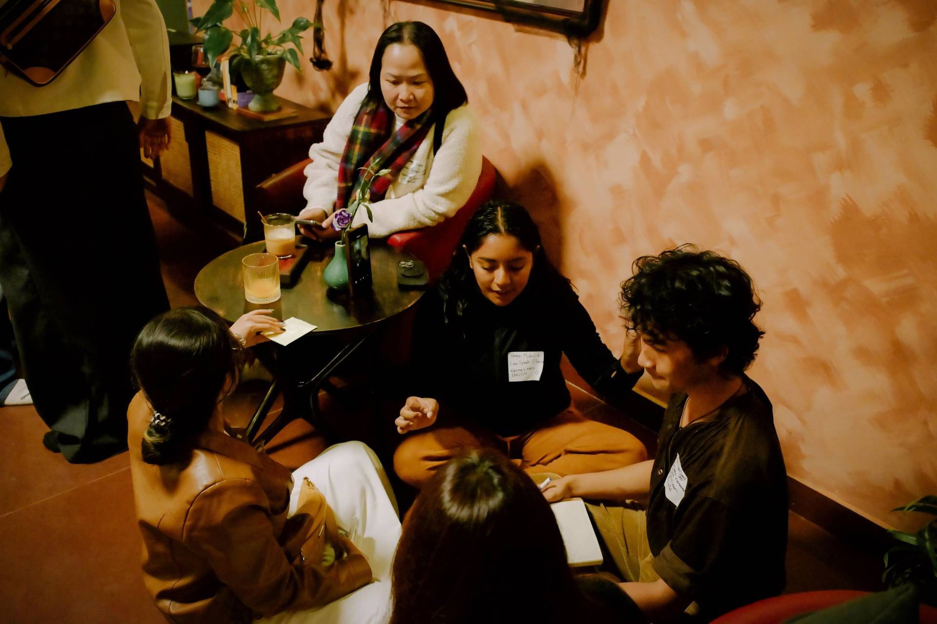 A group of individuals engaged in a collaborative activity around a low table in a cozy café setting in Đà Lạt, Vietnam.