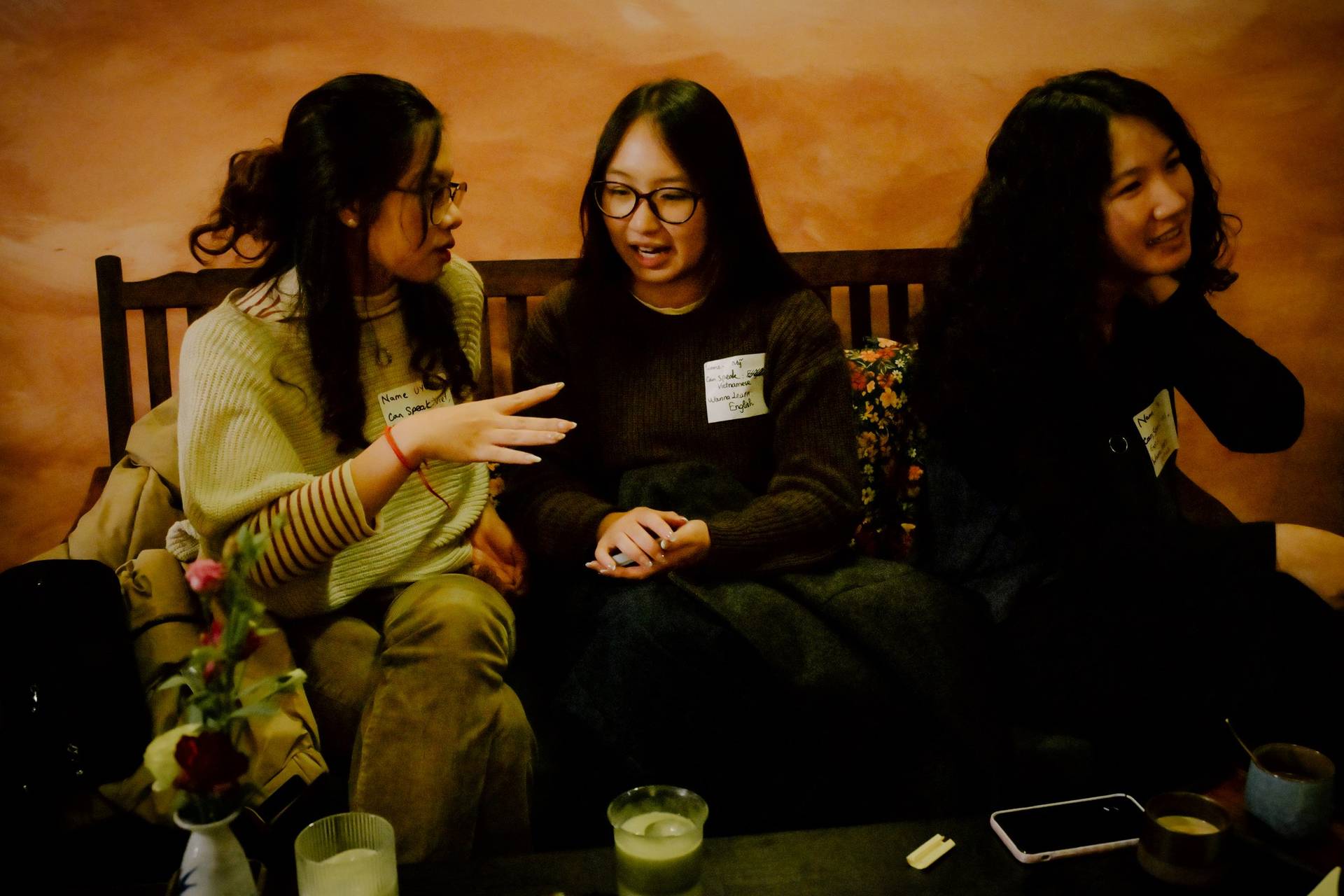 A group of friends engaged in conversation over drinks in a cozy café setting in Đà Lạt, Vietnam.