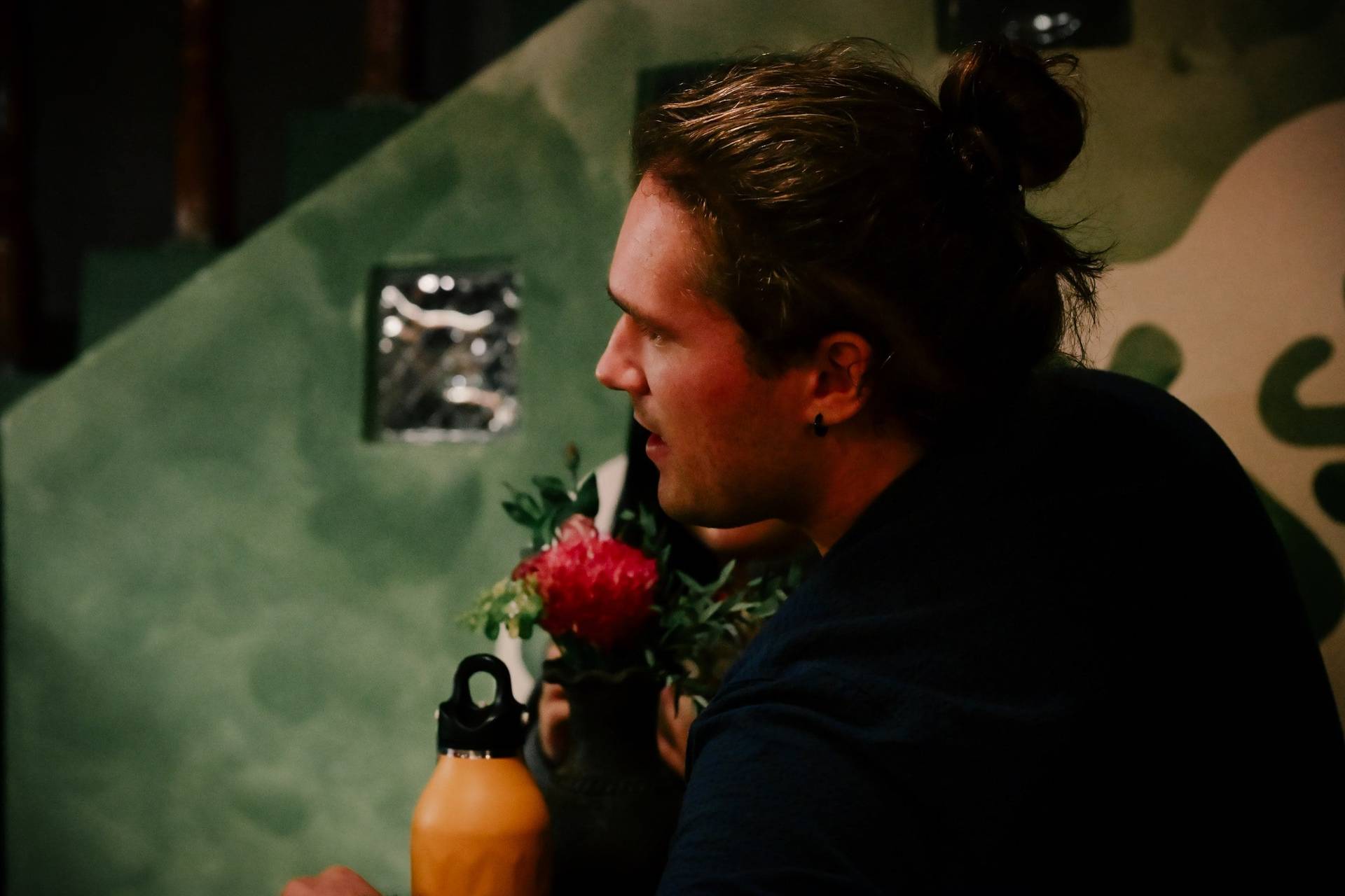 A man with a bun hairstyle is speaking into a microphone during what appears to be a presentation or talk in Đà Lạt, Vietnam.