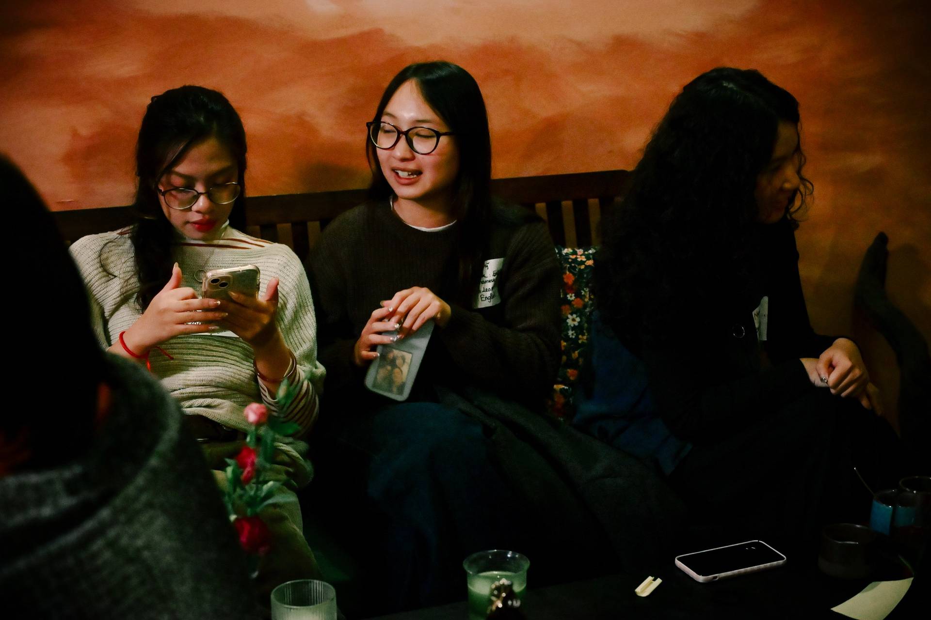 A group of friends enjoys a cozy evening in Đà Lạt, Vietnam, sharing laughter and technology amidst warm lighting.