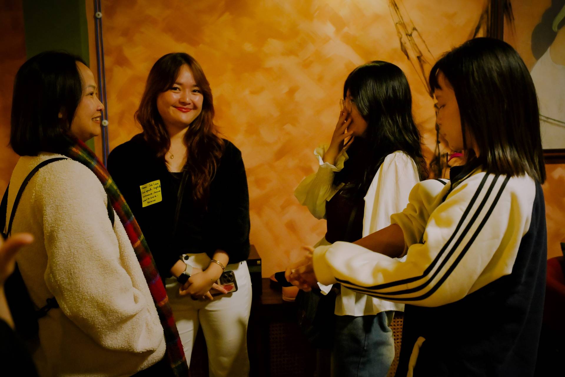 A group of friends gather in a cozy setting in Đà Lạt, Vietnam, sharing laughter and conversation over drinks.