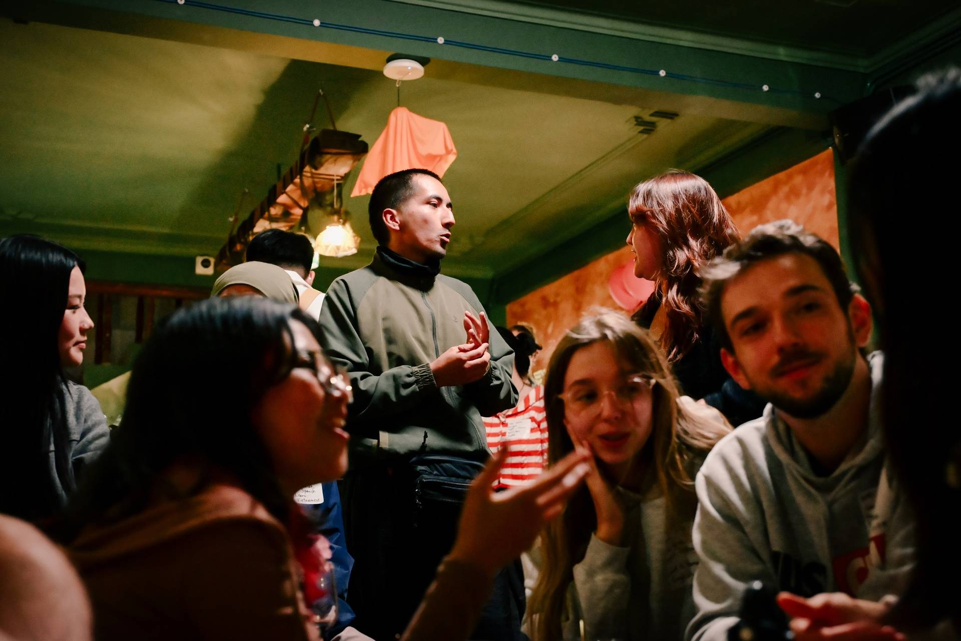 A lively gathering of friends in a cozy bar setting in Đà Lạt, Vietnam, engaging in animated conversation and laughter.