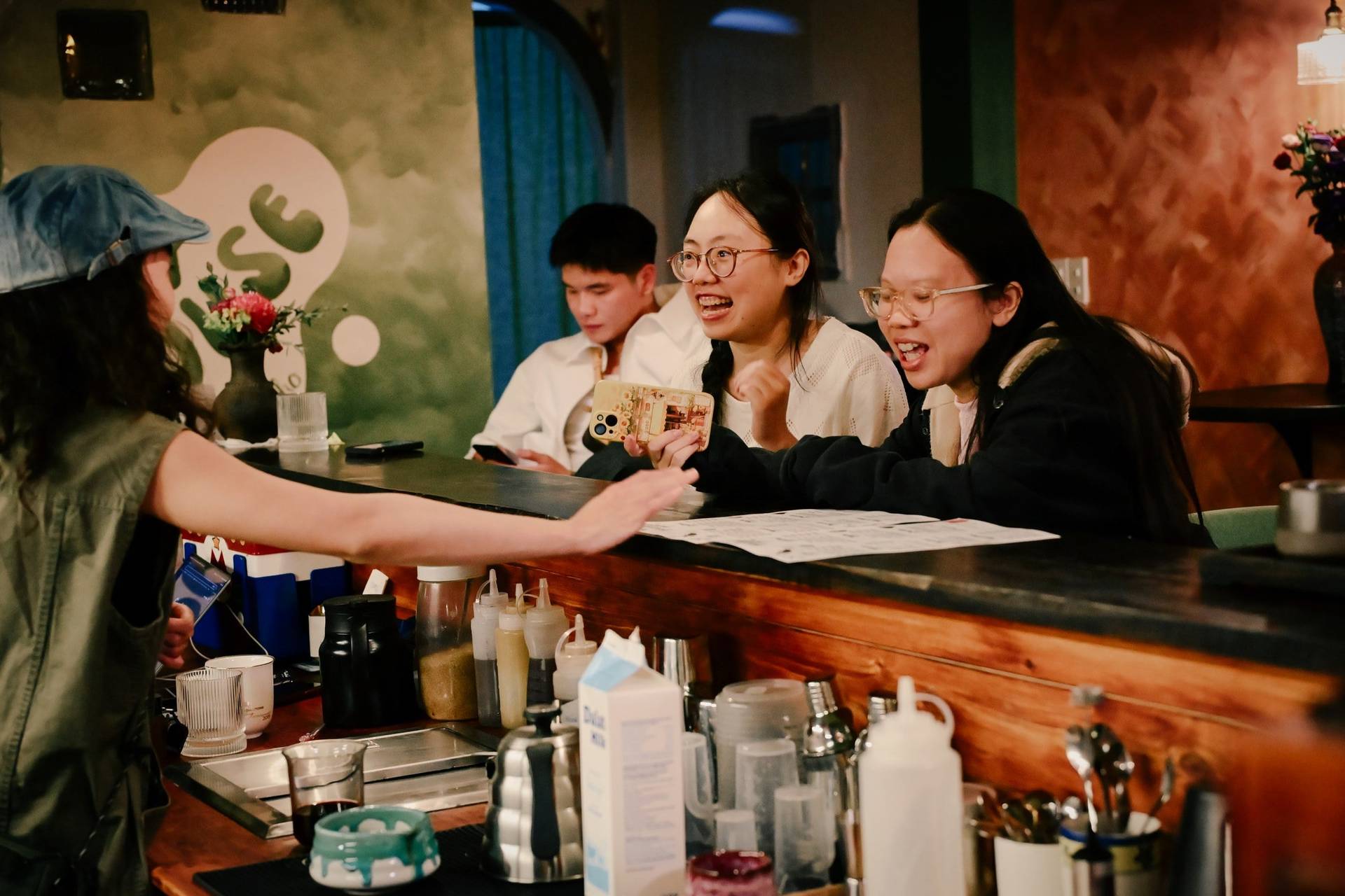 A group of friends enjoys a lively conversation over drinks in a cozy café setting in Đà Lạt, Vietnam.