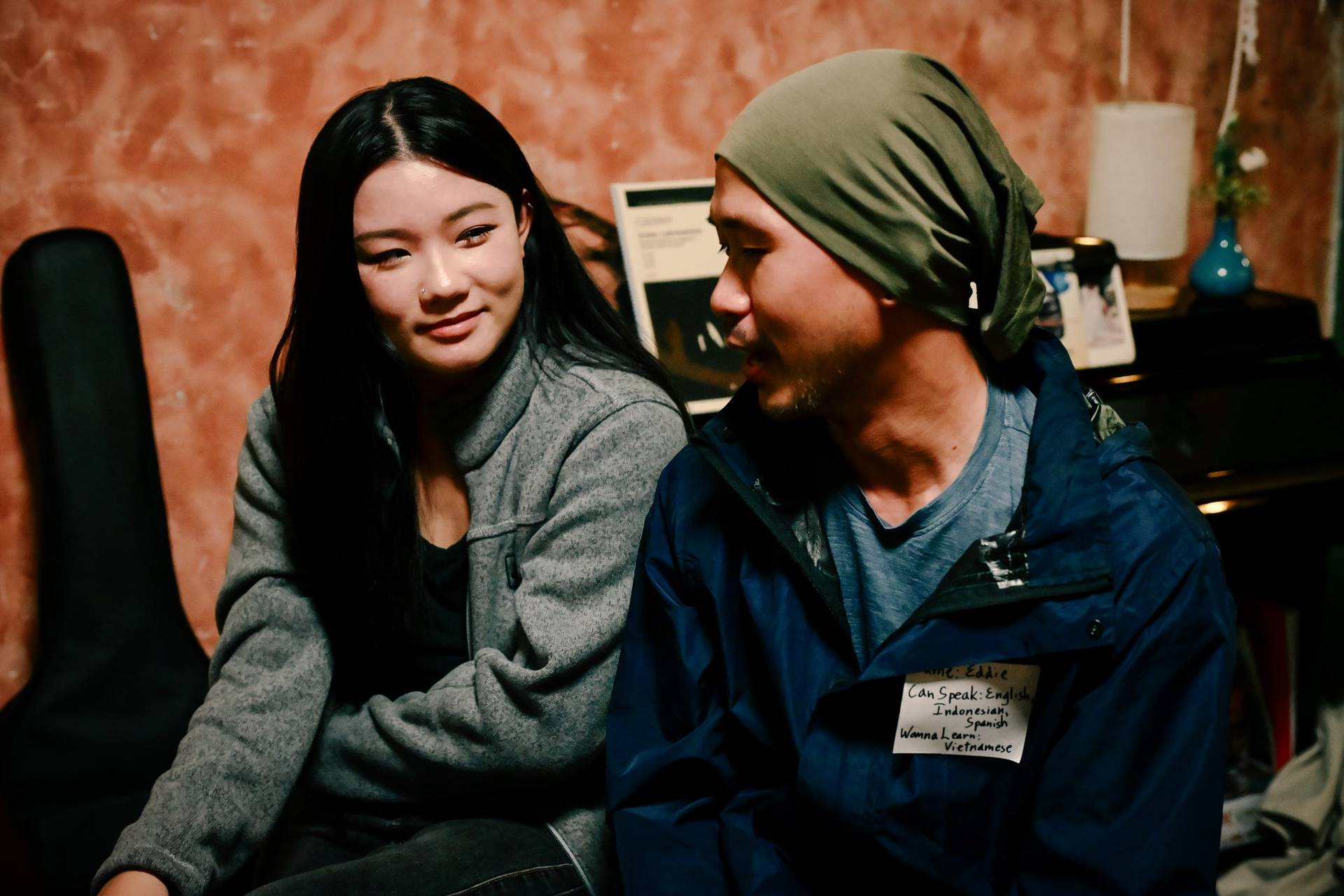 Two individuals engaged in conversation during a social gathering in Đà Lạt, Vietnam, with a cozy and intimate atmosphere.