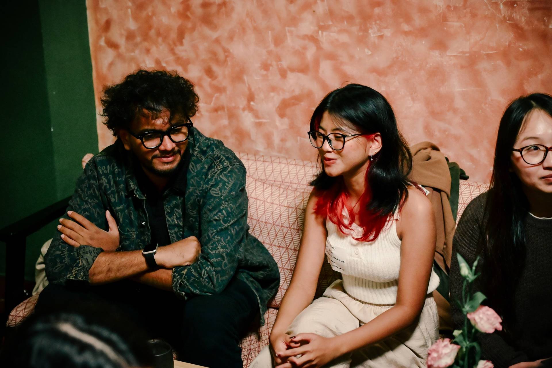 A group of individuals is seated in a cozy setting with warm lighting, engaging in conversation or listening attentively during an event in Đà Lạt, Vietnam.