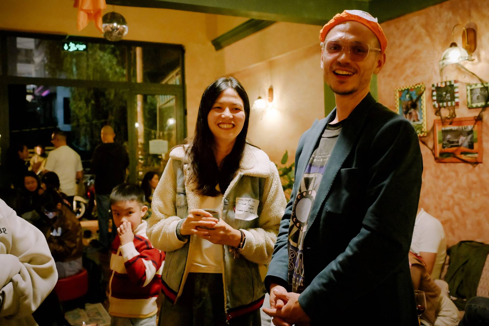 A lively gathering in a cozy café in Đà Lạt, Vietnam, with people enjoying drinks and socializing under warm lighting.