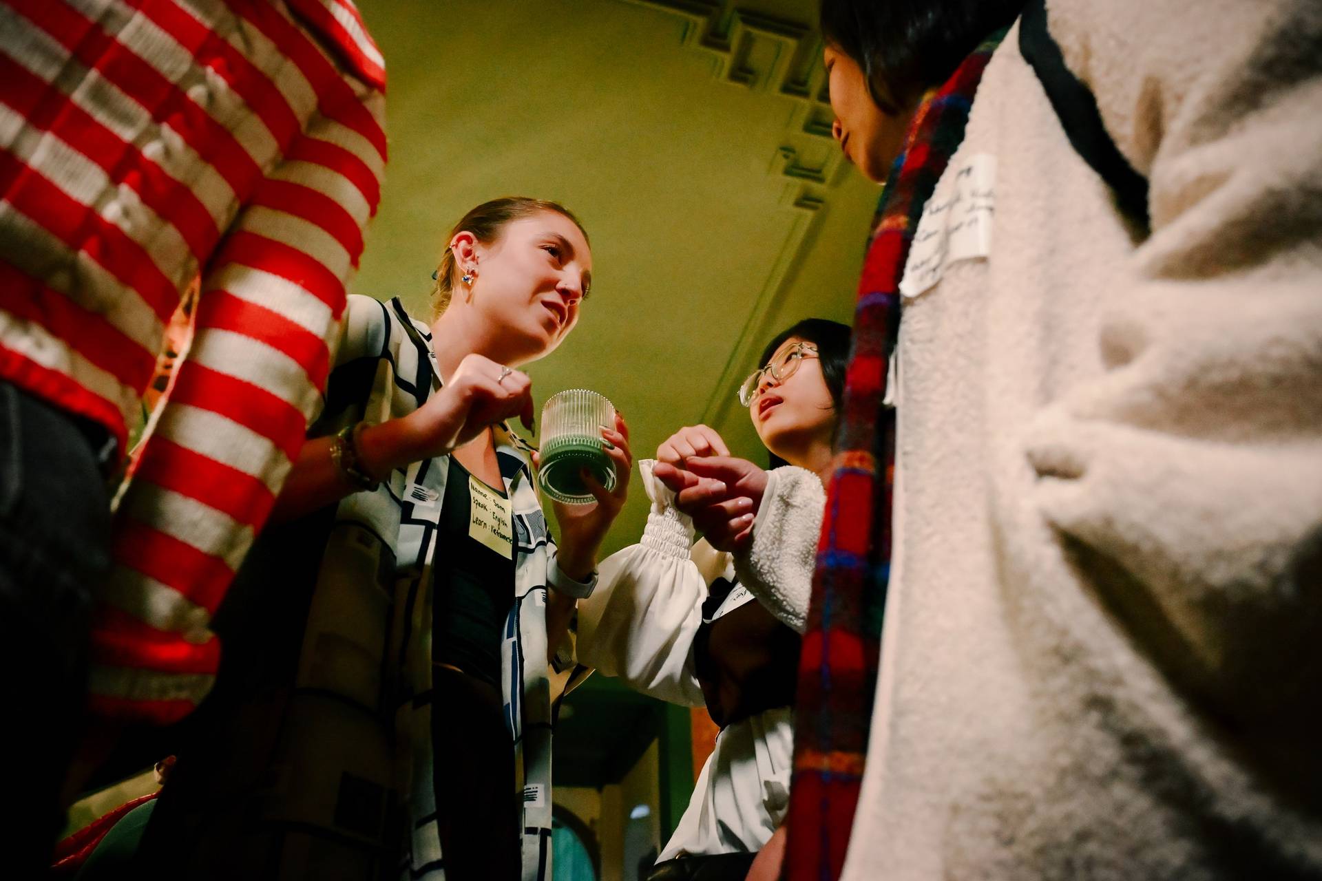 A group of friends engage in a lively discussion while exploring traditional Vietnamese textiles during an evening event in Đà Lạt.
