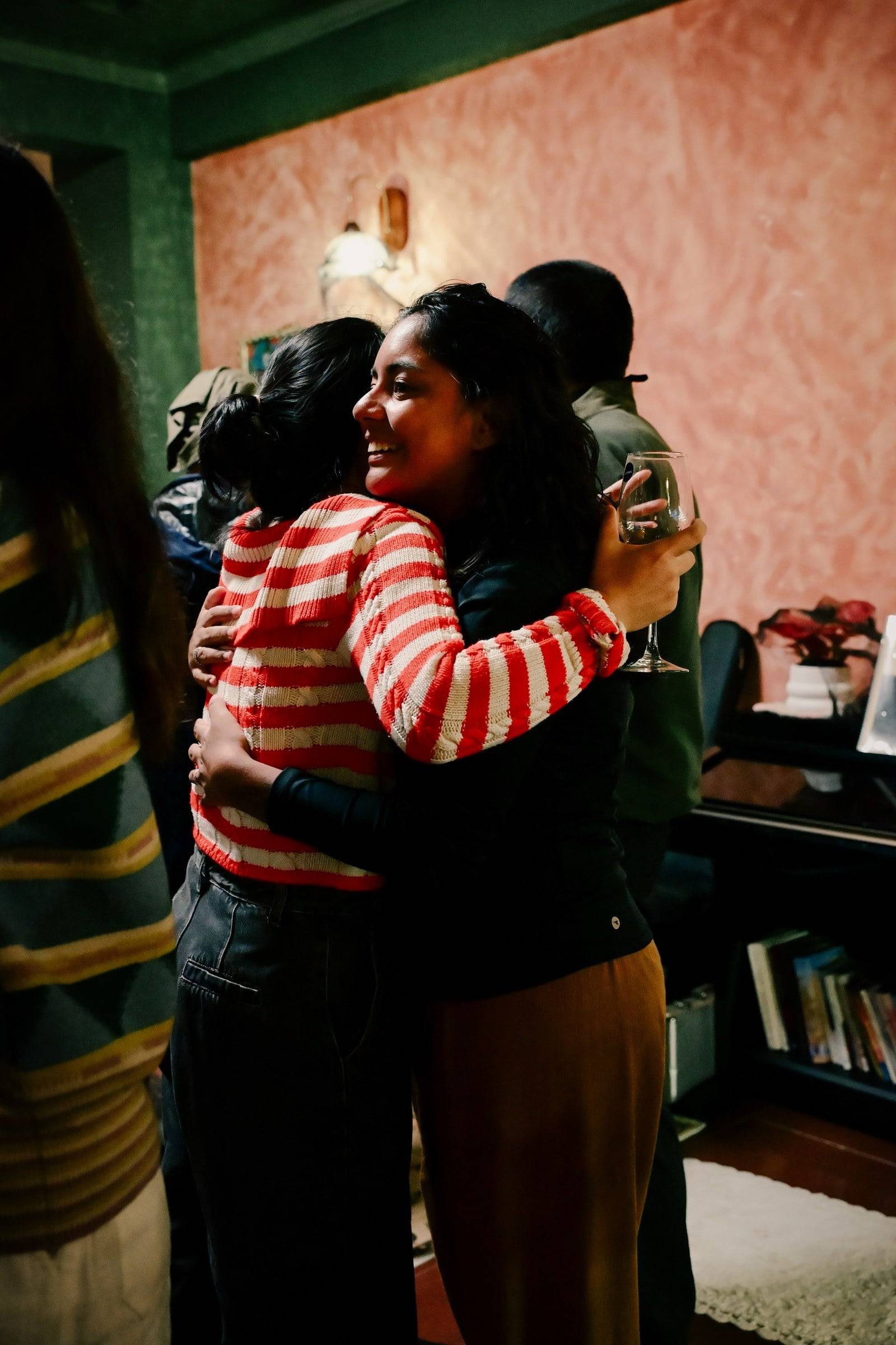 A warm embrace between friends in a cozy indoor setting, capturing the essence of camaraderie and joy during a social gathering in Đà Lạt.