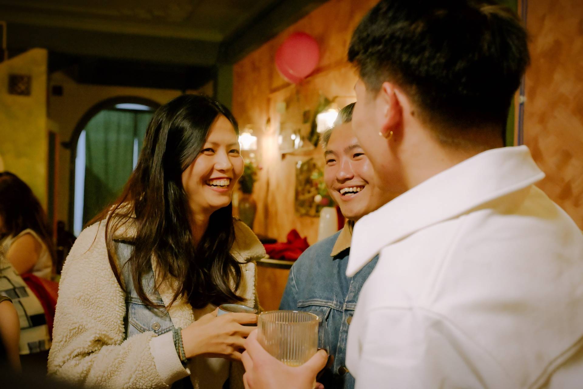 A group of friends share a joyful moment in a cozy café setting in Đà Lạt, Vietnam, surrounded by warm lighting and festive decorations.