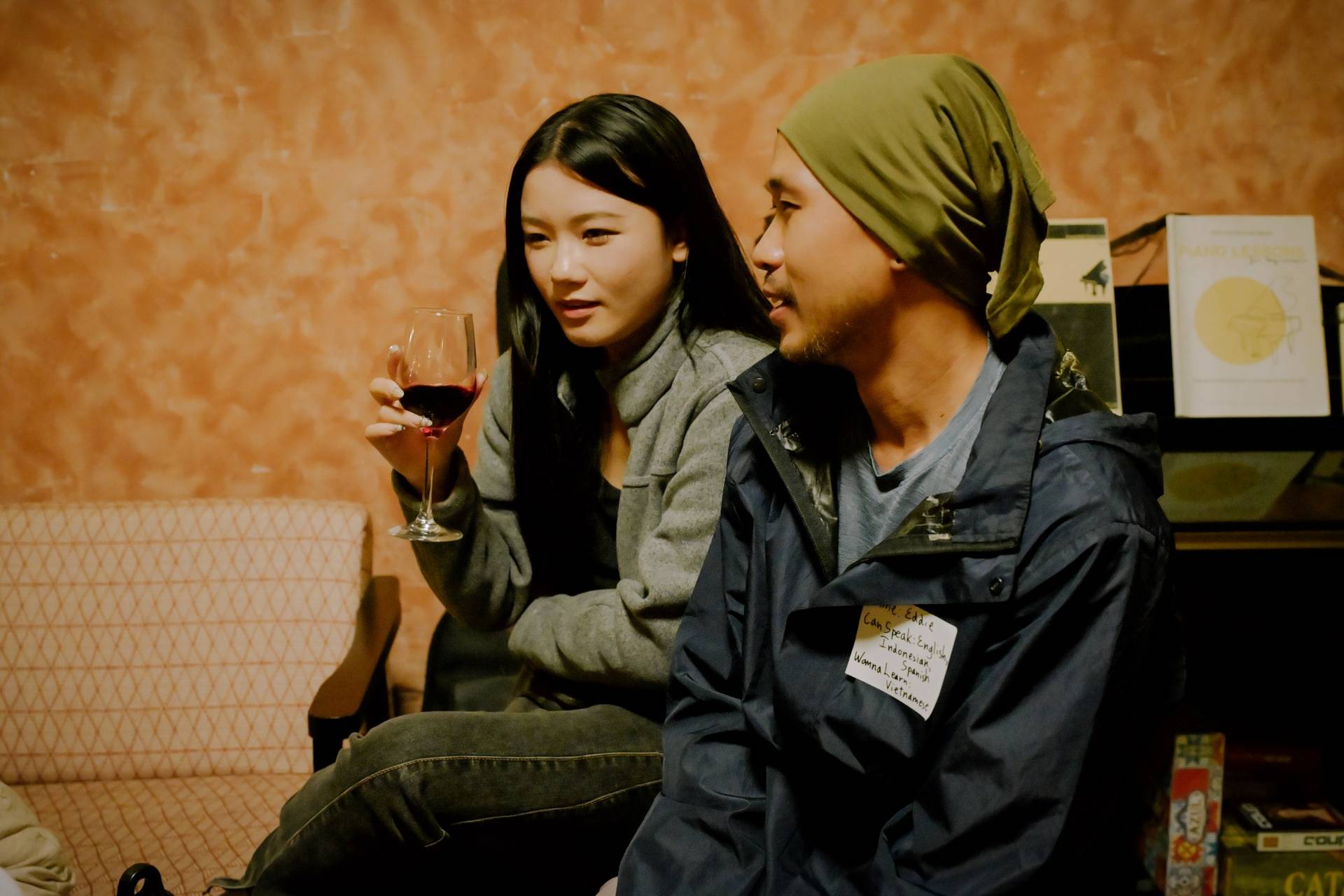 Two individuals engage in a relaxed conversation over wine in a cozy setting within Đà Lạt, Vietnam.