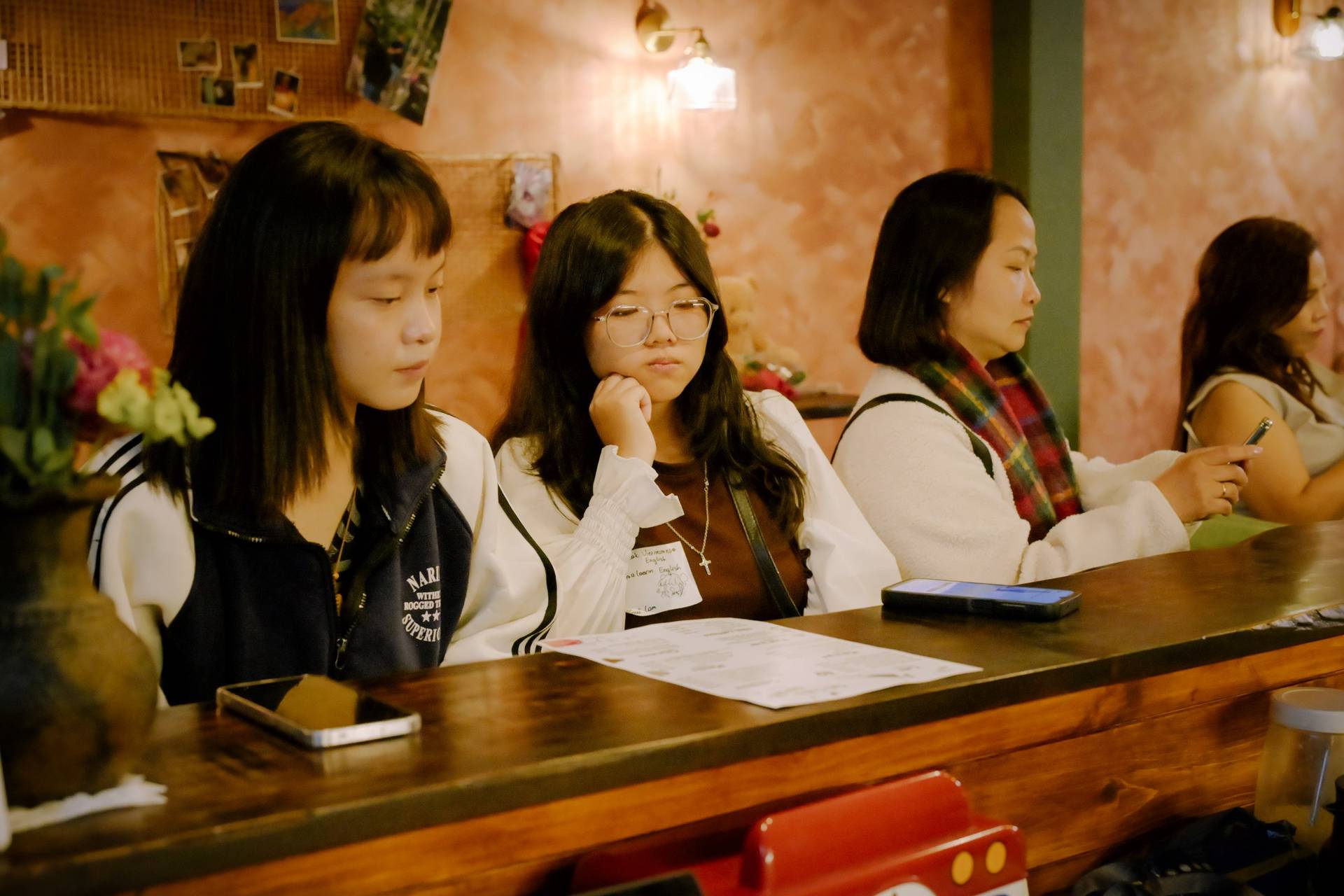A group of friends gathered in a cozy café in Đà Lạt, Vietnam, engaged in conversation and enjoying their time together over drinks.