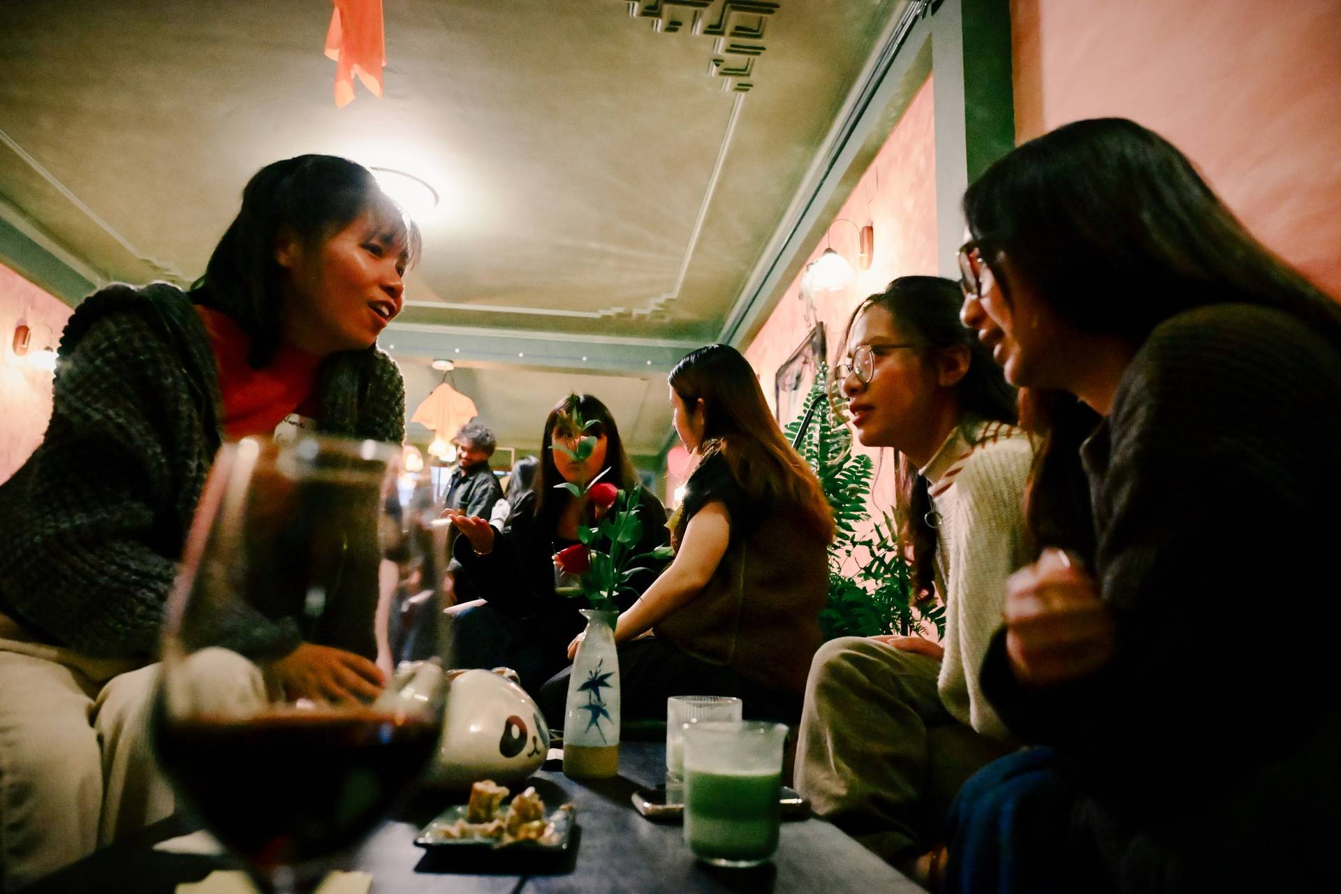 A group of friends enjoys a cozy evening in Đà Lạt, Vietnam, sharing laughter and drinks around a table adorned with traditional Vietnamese decor.