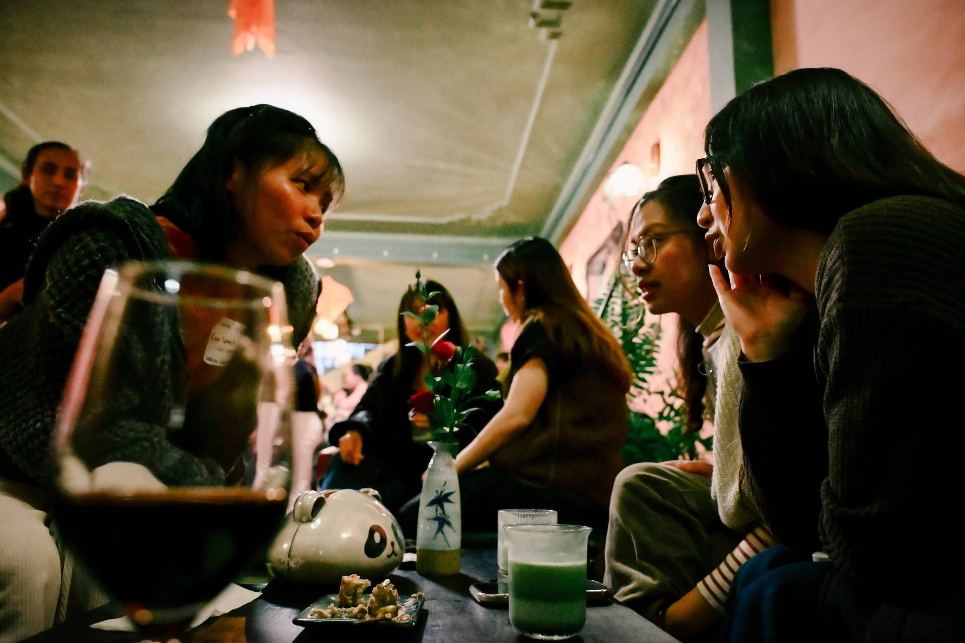 A group of friends enjoys a cozy evening in Đà Lạt, Vietnam, sharing drinks and laughter around a table adorned with traditional Vietnamese decor.