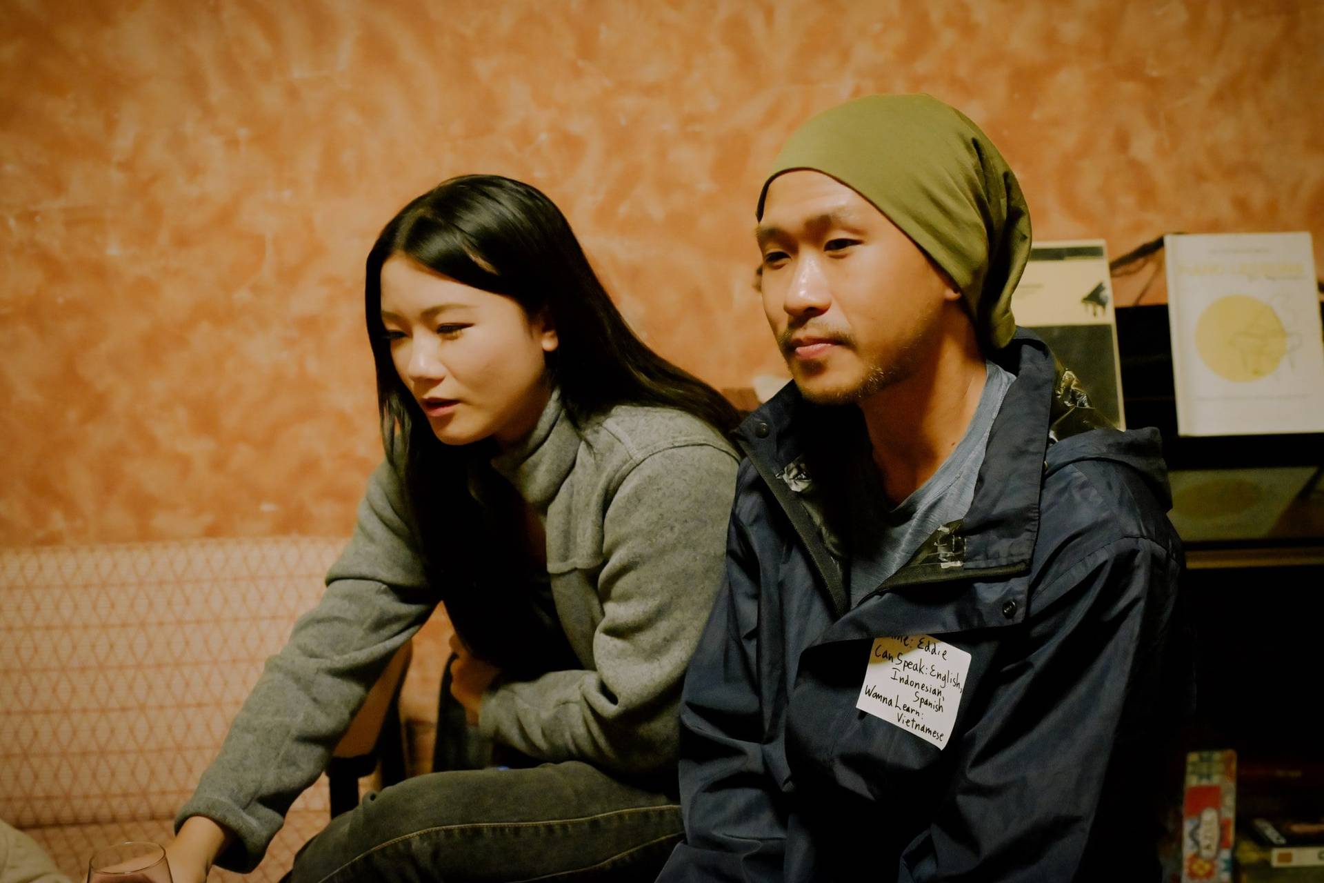 Two individuals seated in a cozy café setting in Đà Lạt, Vietnam, engaged in conversation with a relaxed and intimate atmosphere.