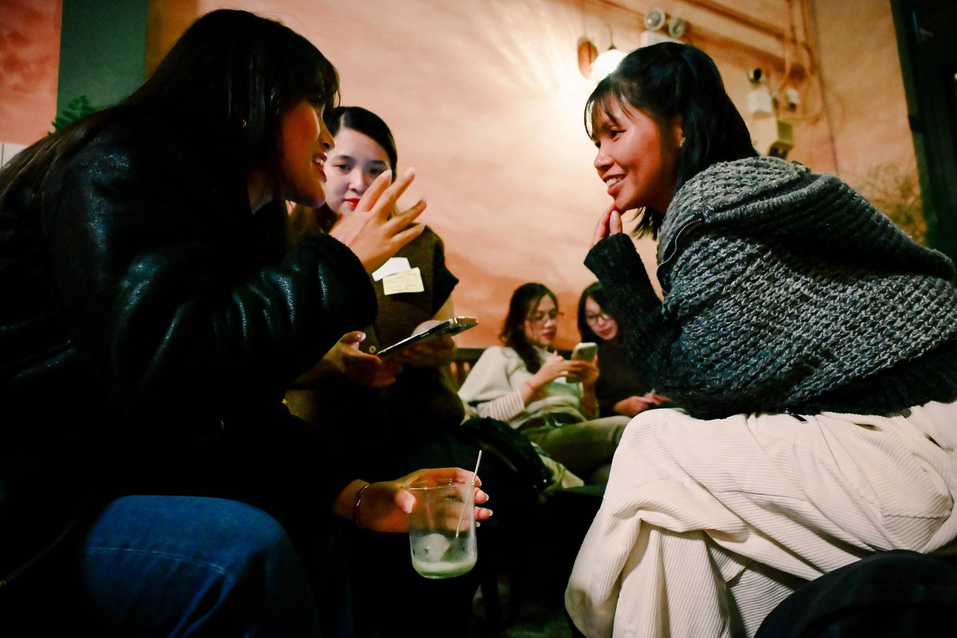 A group of friends enjoys a cozy evening in Đà Lạt, Vietnam, sharing laughter and drinks while engaging with each other.