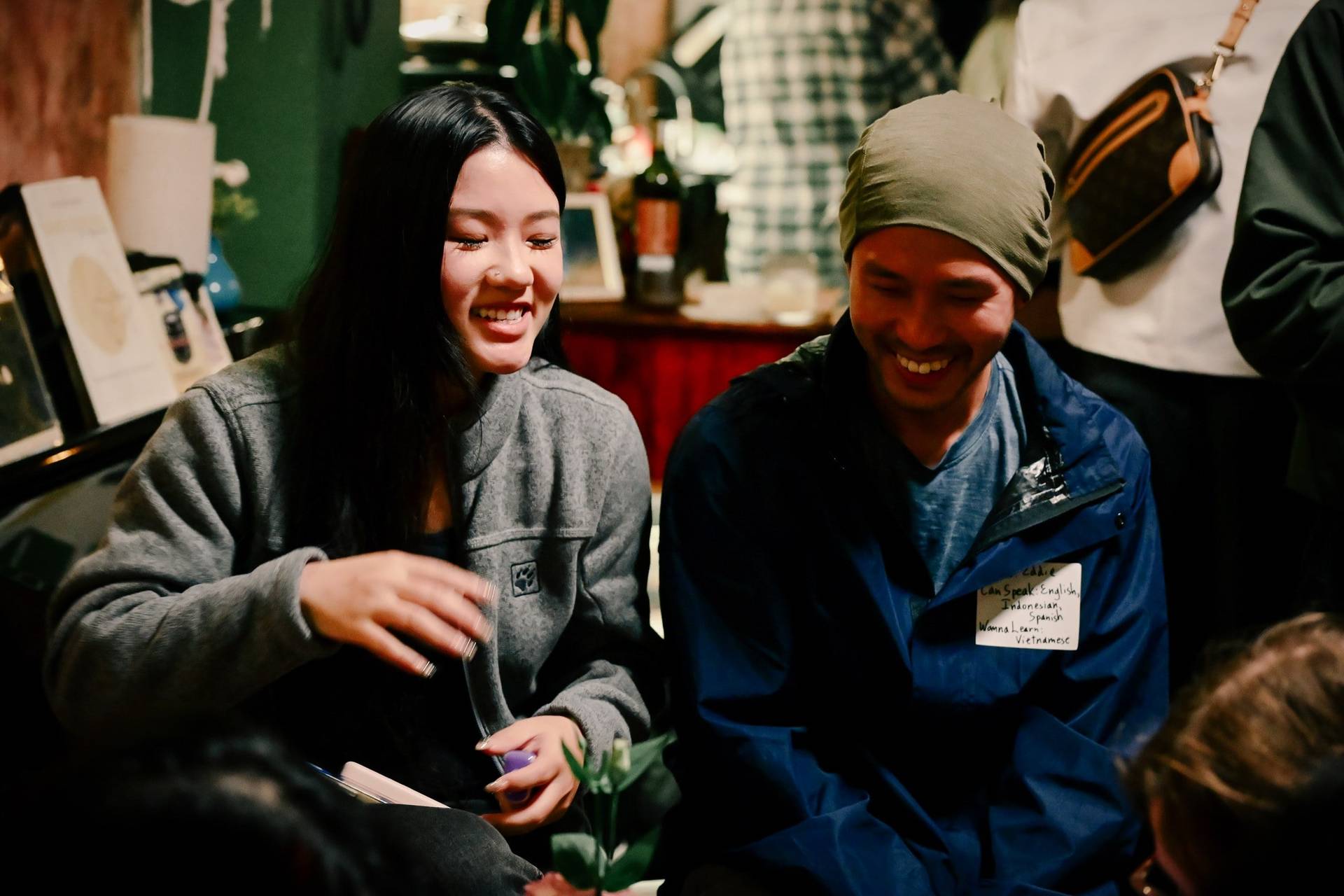A group of friends share laughter over a board game in a cozy café setting in Đà Lạt, Vietnam.