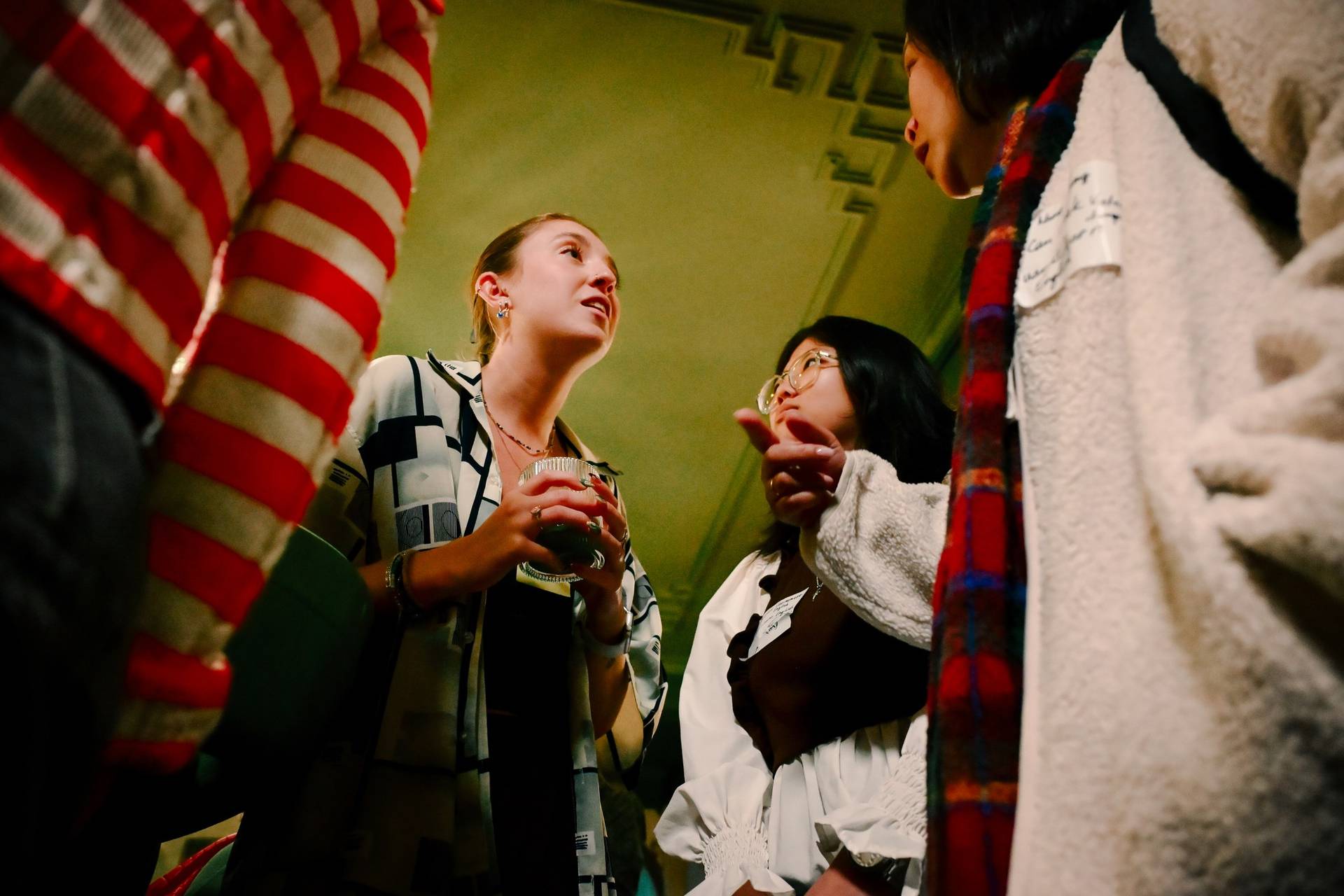 A group of individuals engaged in a lively discussion during an indoor gathering in Đà Lạt, Vietnam, with festive decorations and warm lighting creating a cozy atmosphere.