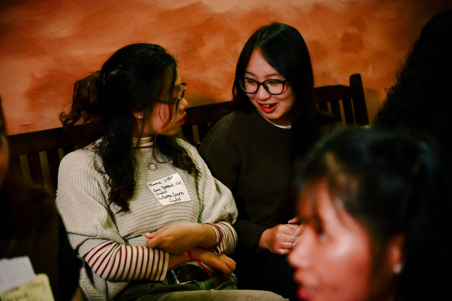 Two friends share a warm moment during a social gathering in Đà Lạt, Vietnam, surrounded by cozy ambiance and friendly interactions.