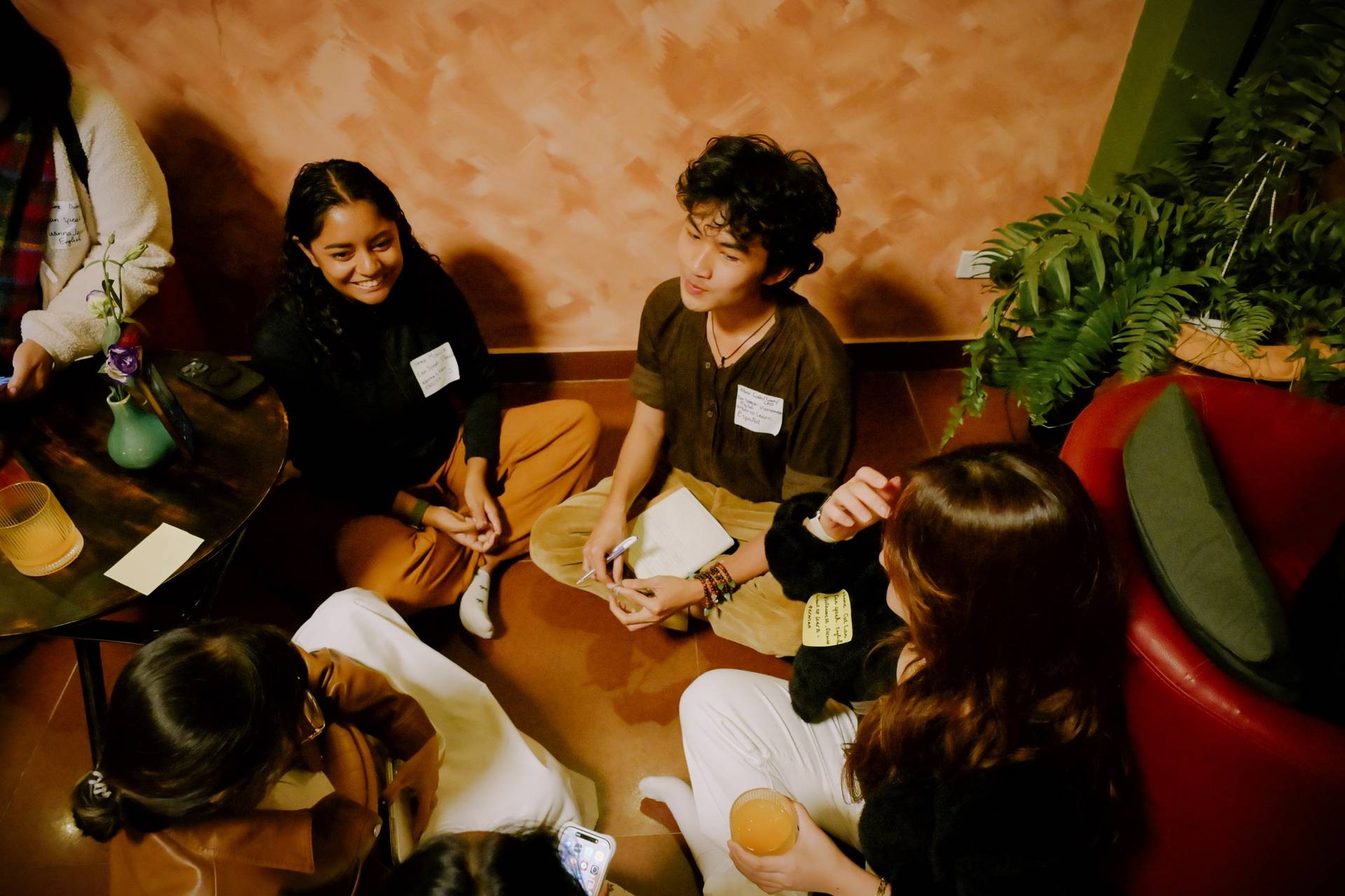 A group of friends enjoys a cozy gathering in Đà Lạt, Vietnam, engaging in conversation and laughter over drinks and snacks.