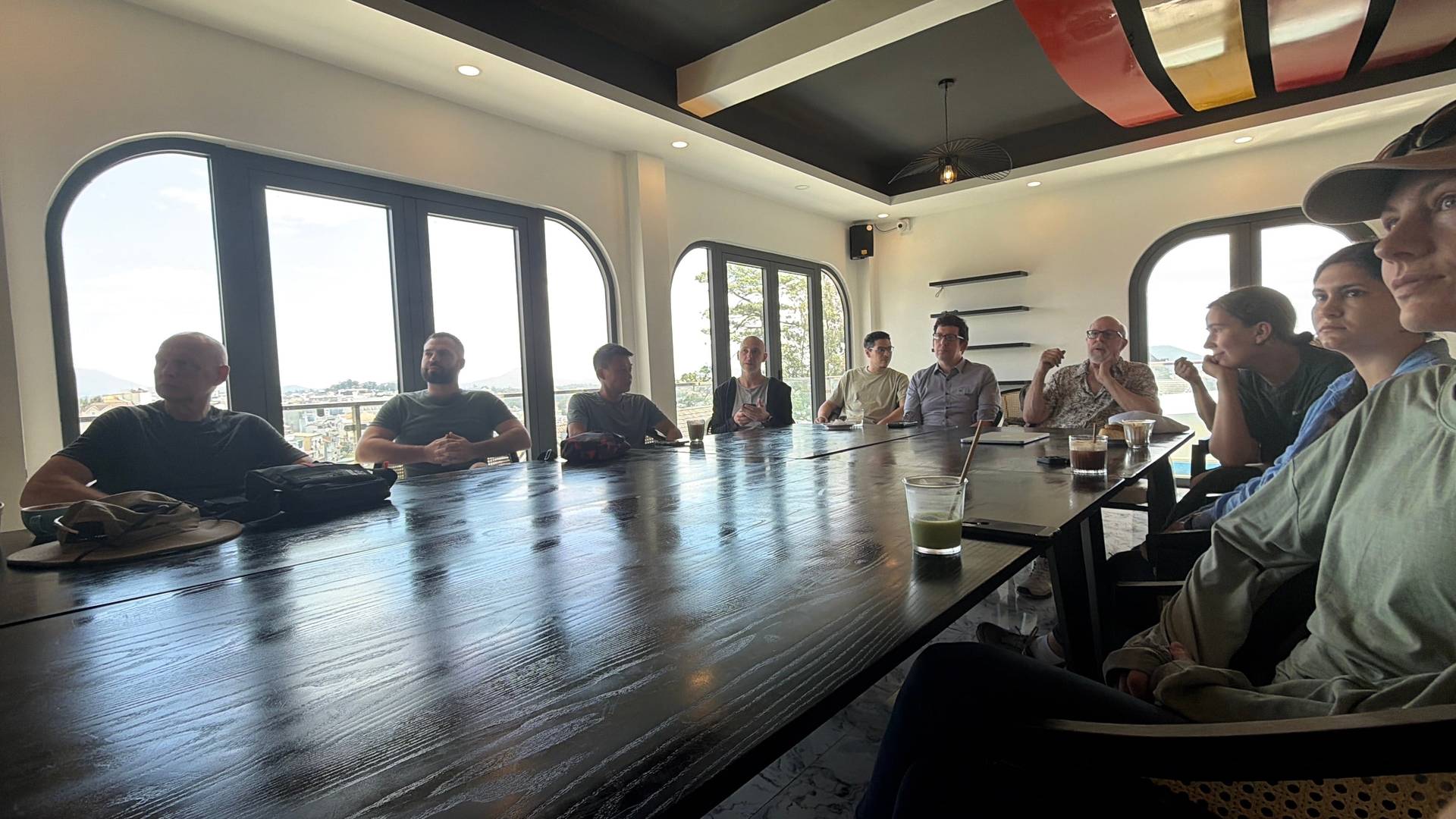 Conference panel or discussion session at a Đà Lạt high-altitude event venue, with participants gathered around a table overlooking the city valley landscape