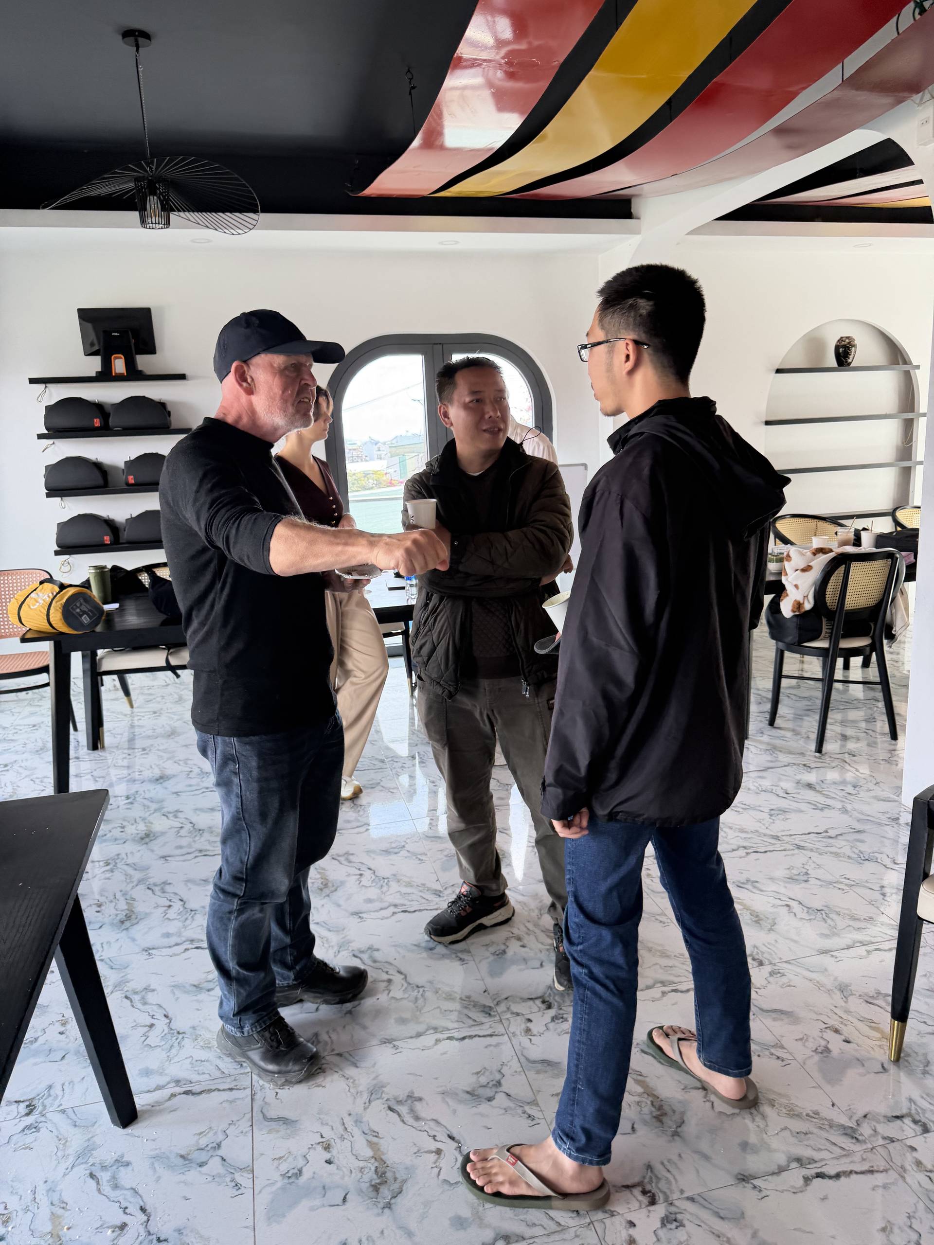 Networking moment at a Đà Lạt event with striking geometric ceiling design and modern décor, guests mingling in an upscale venue with decorative shelving and ambient lighting.