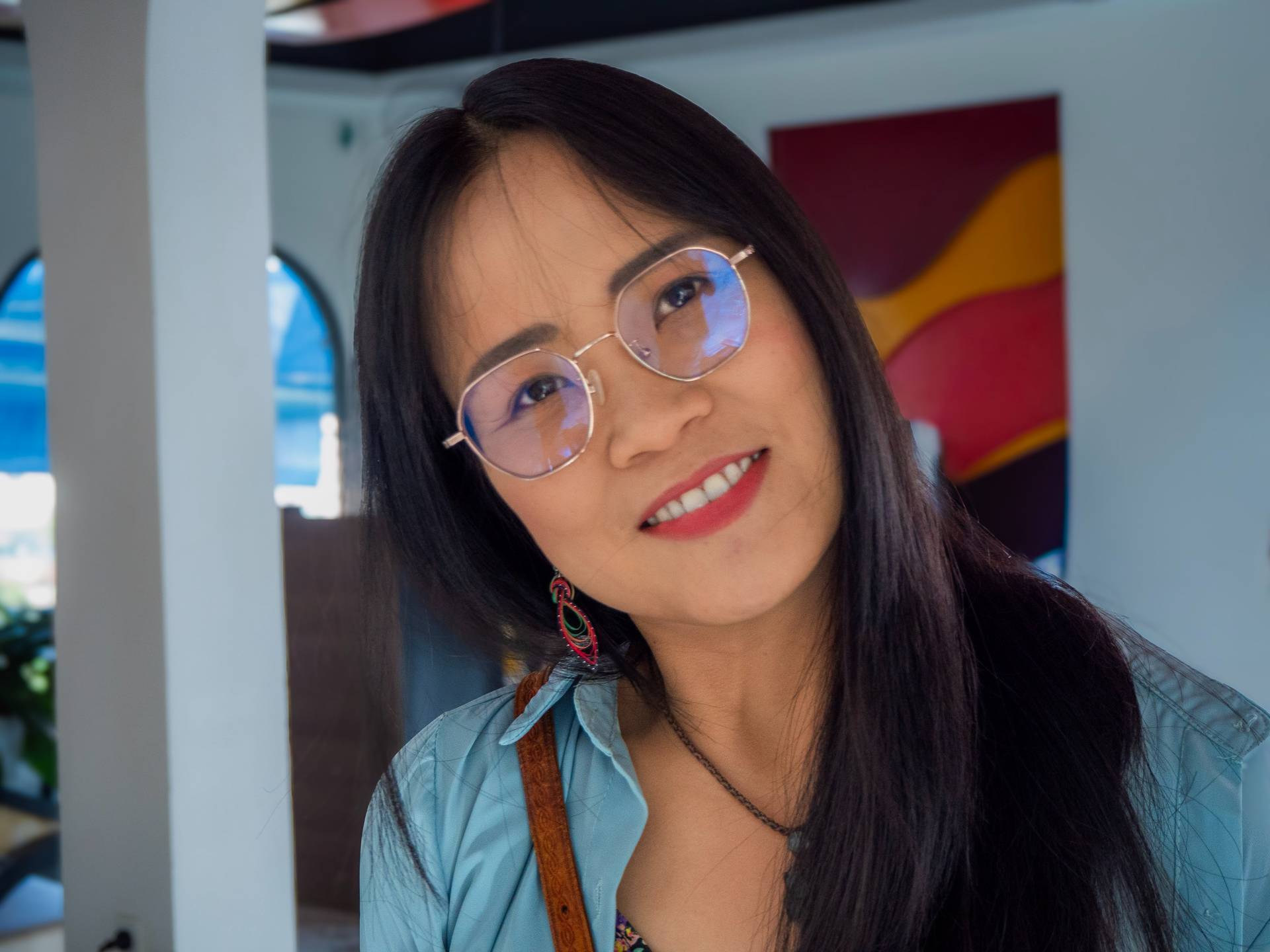 Smiling attendee at a modern event venue, photographed indoors with contemporary geometric wall art design in background.