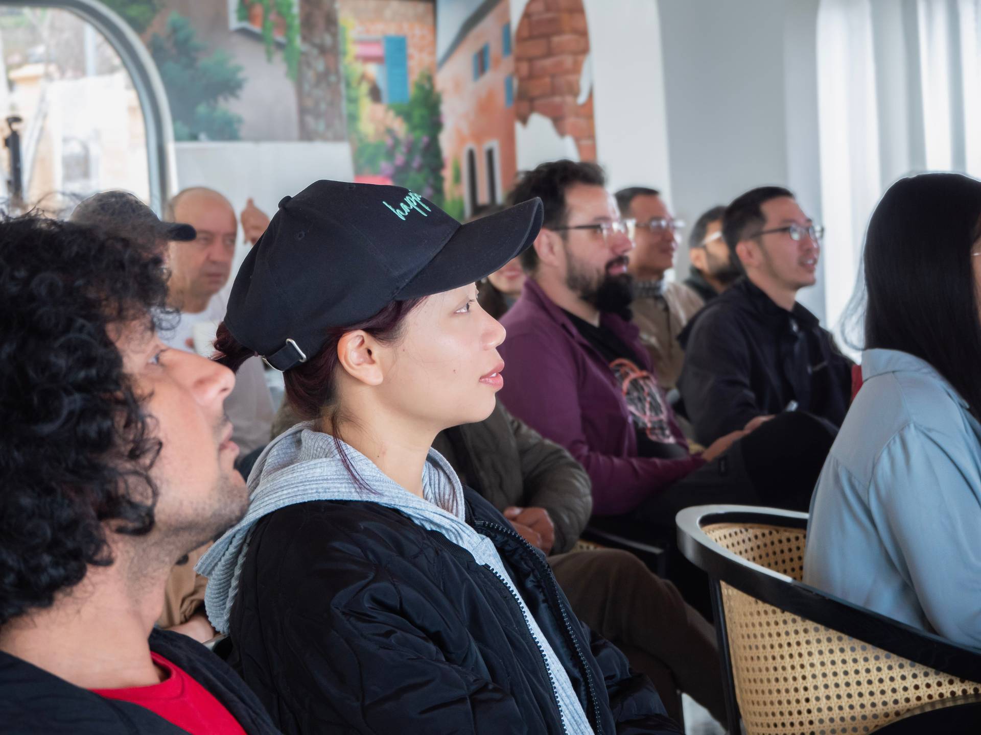A diverse group of hackathon participants gathered indoors at a Đà Lạt event venue, focused on a presentation or demonstration during the tech conference.