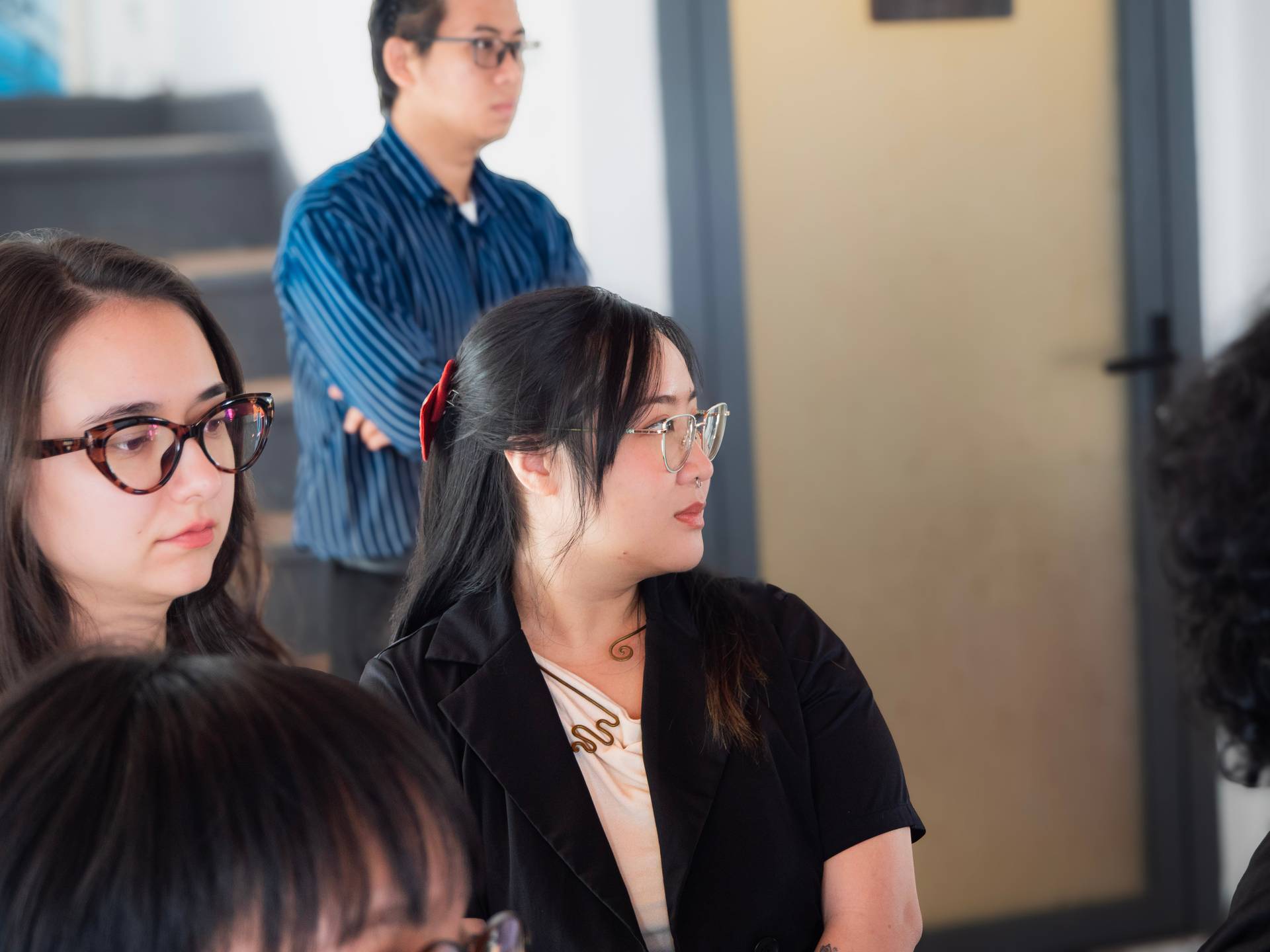 Young professionals seated and attentively listening during a tech workshop or seminar presentation in a bright modern space.