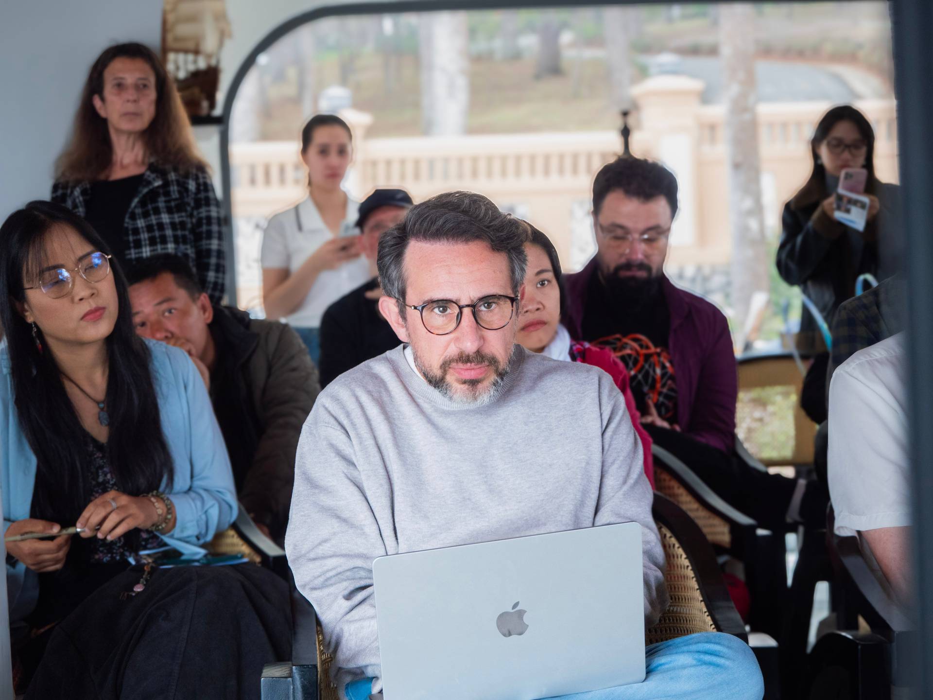 A diverse group gathers in a modern Đà Lạt venue to watch a presentation or workshop session. The collaborative atmosphere and attentive audience reflect active engagement with shared learning and networking.