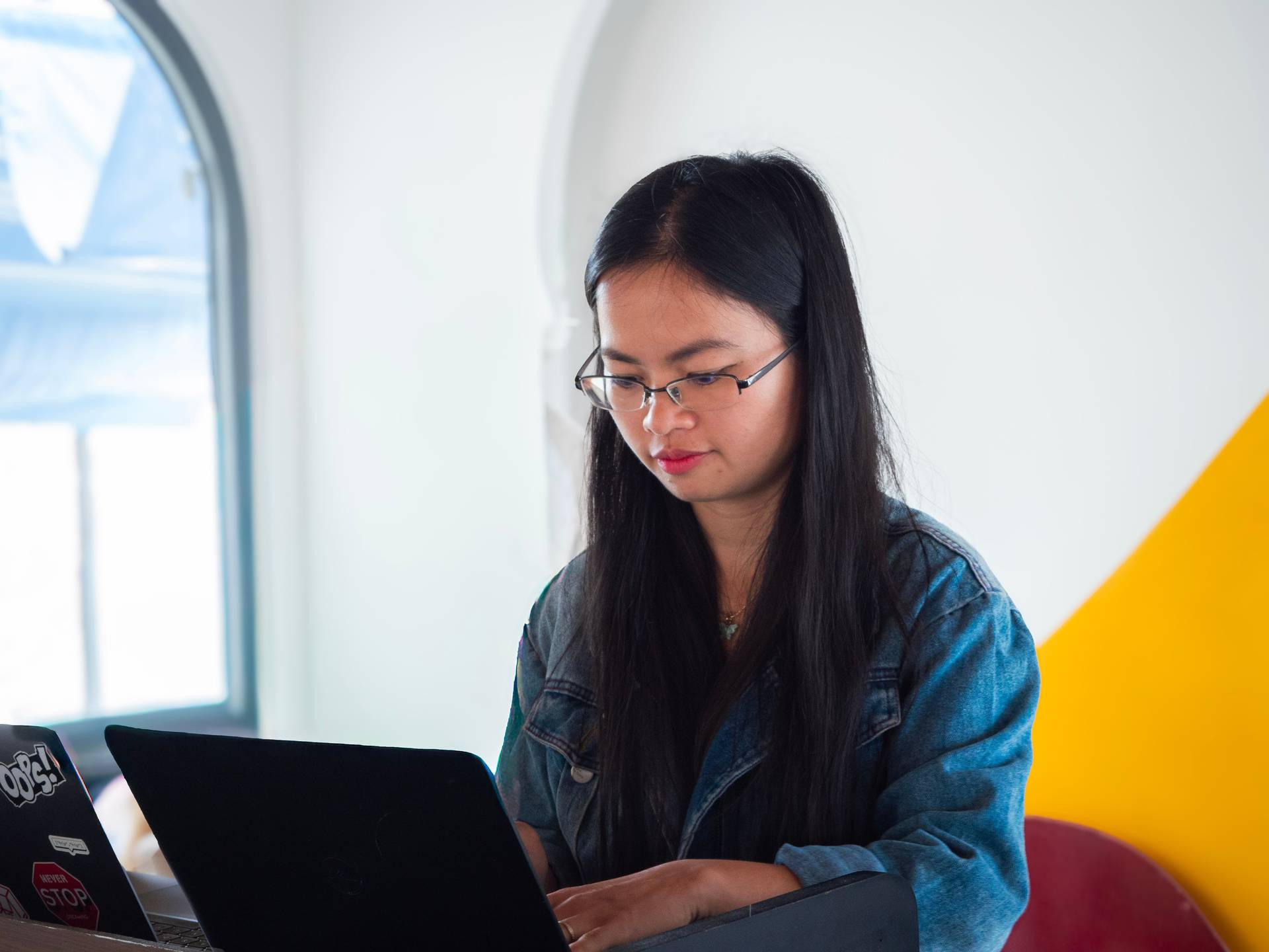 A productive workspace moment captured in a modern Đà Lạt venue, with natural light streaming through large windows. The bright, contemporary office environment supports focused digital work and collaboration.
