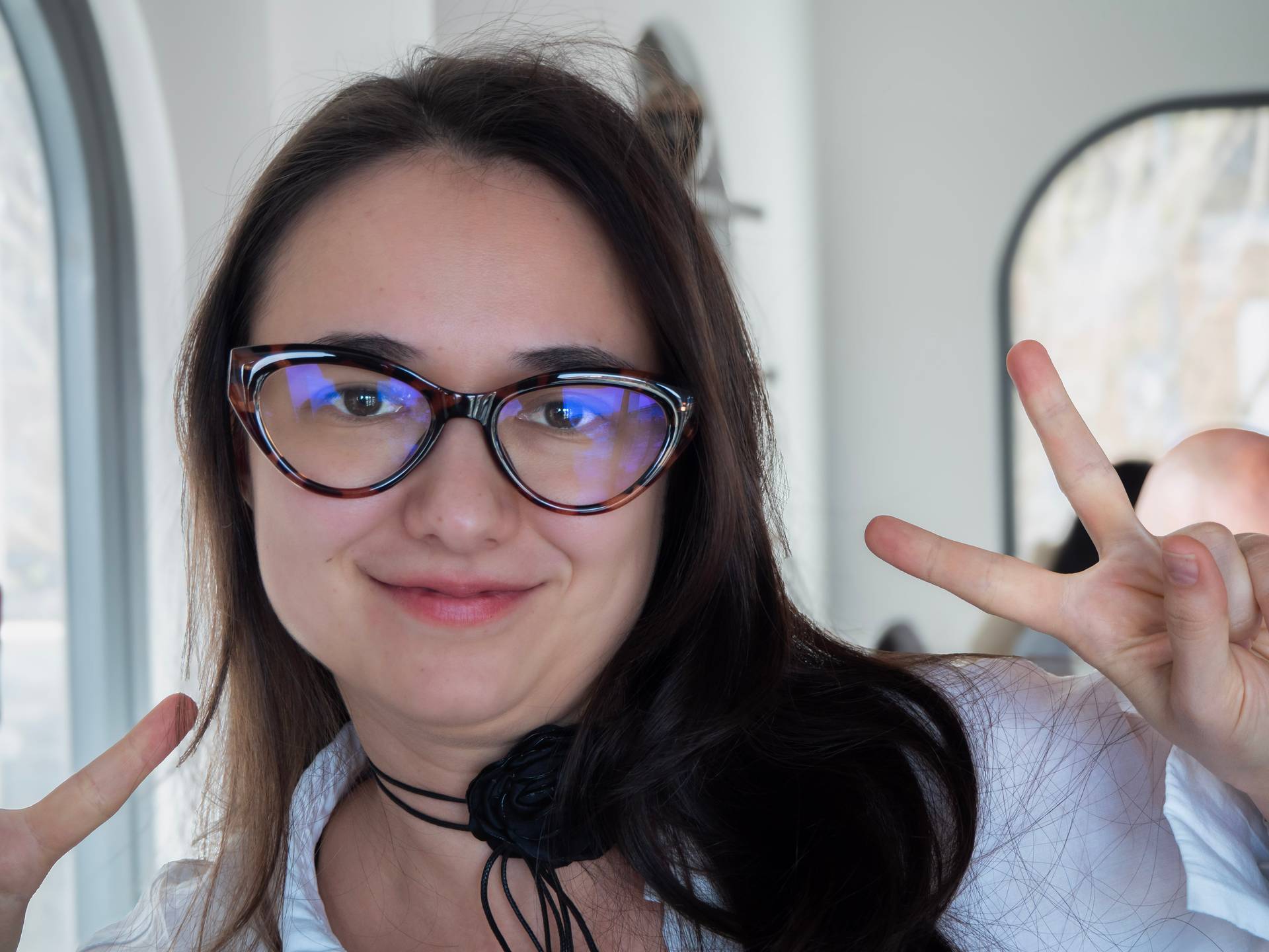 Casual selfie-style portrait during an event in Đà Lạt, capturing a playful moment with a peace sign gesture. Represents the casual, fun side of social gatherings in the creative community.