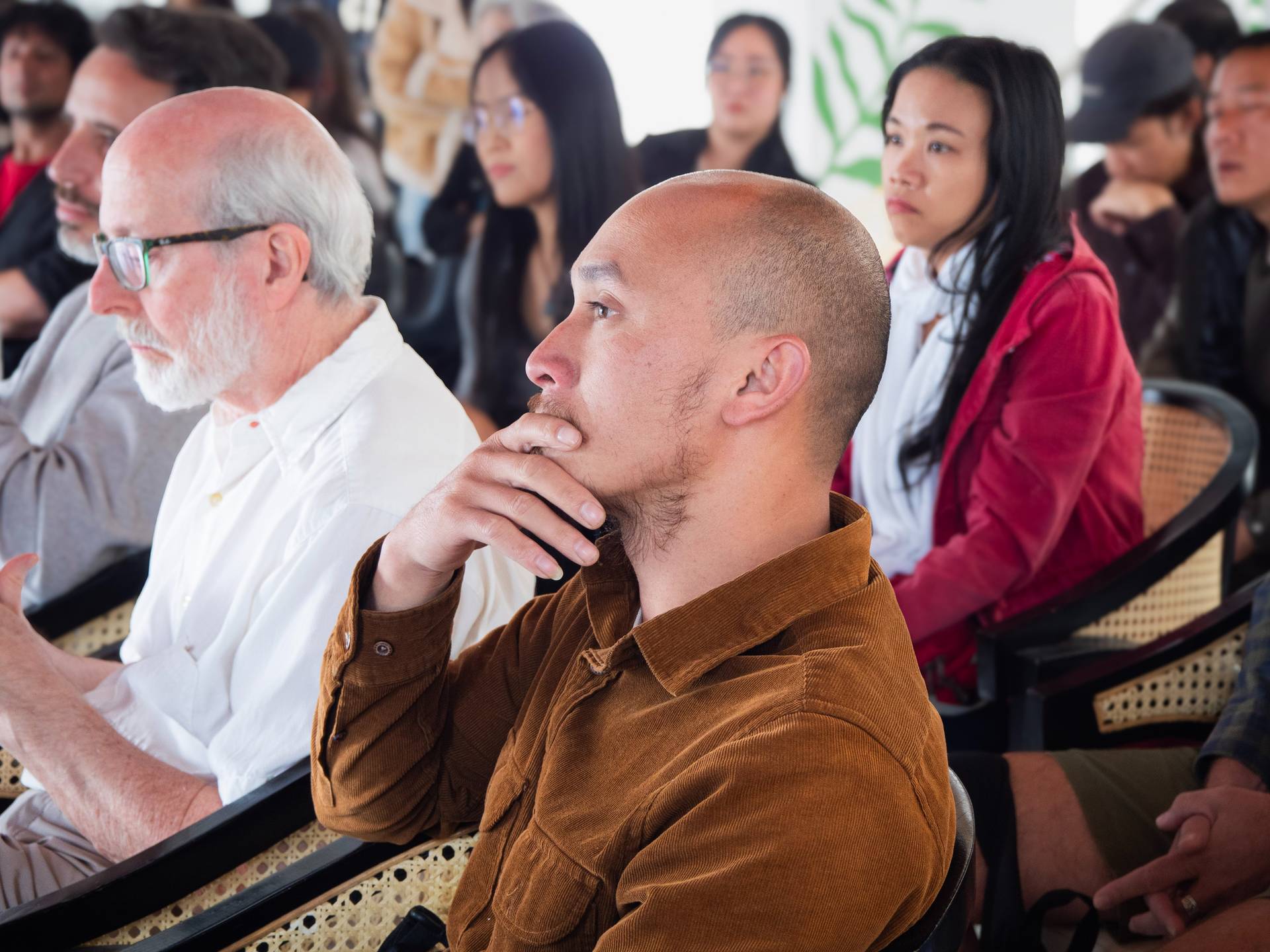 Close-up view of diverse attendees seated at a community workshop, showing engaged and thoughtful expressions during a presentation.