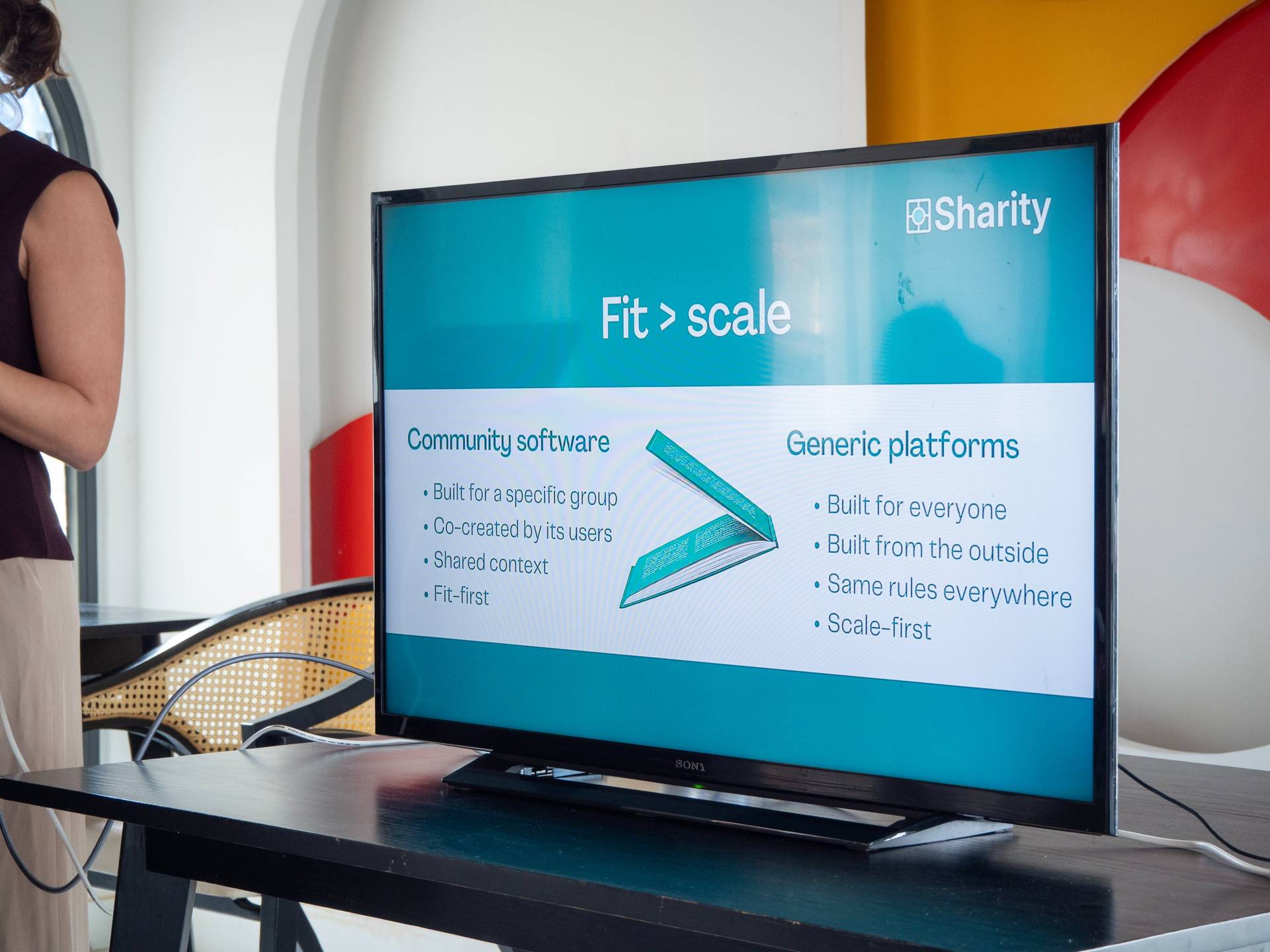 Projection screen displaying Sharity branding and 'Fit > scale' framework comparing community software versus generic platforms.