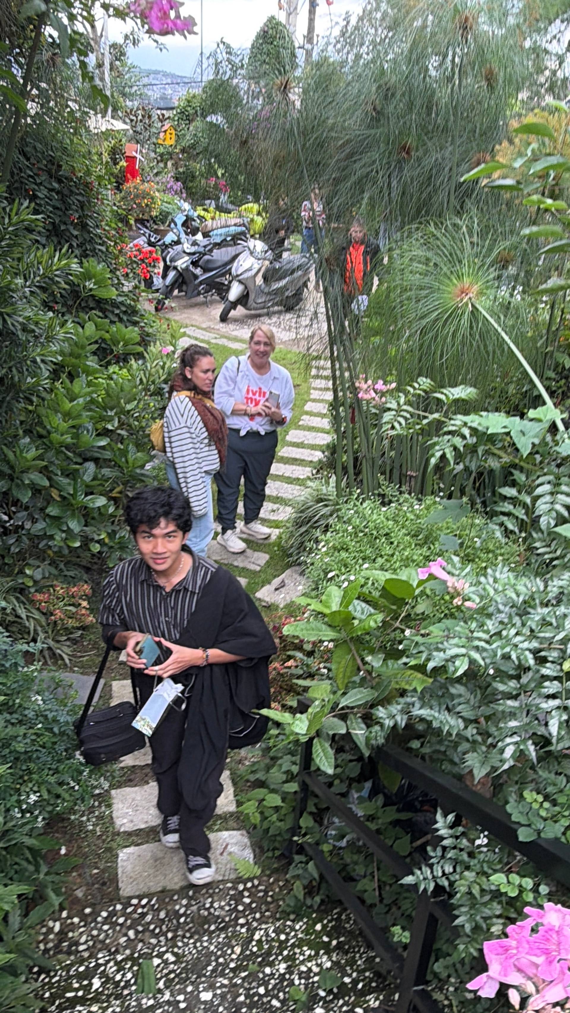 A group of people enjoying a leisurely stroll through a lush garden in Đà Lạt, Vietnam, surrounded by vibrant flowers and greenery.