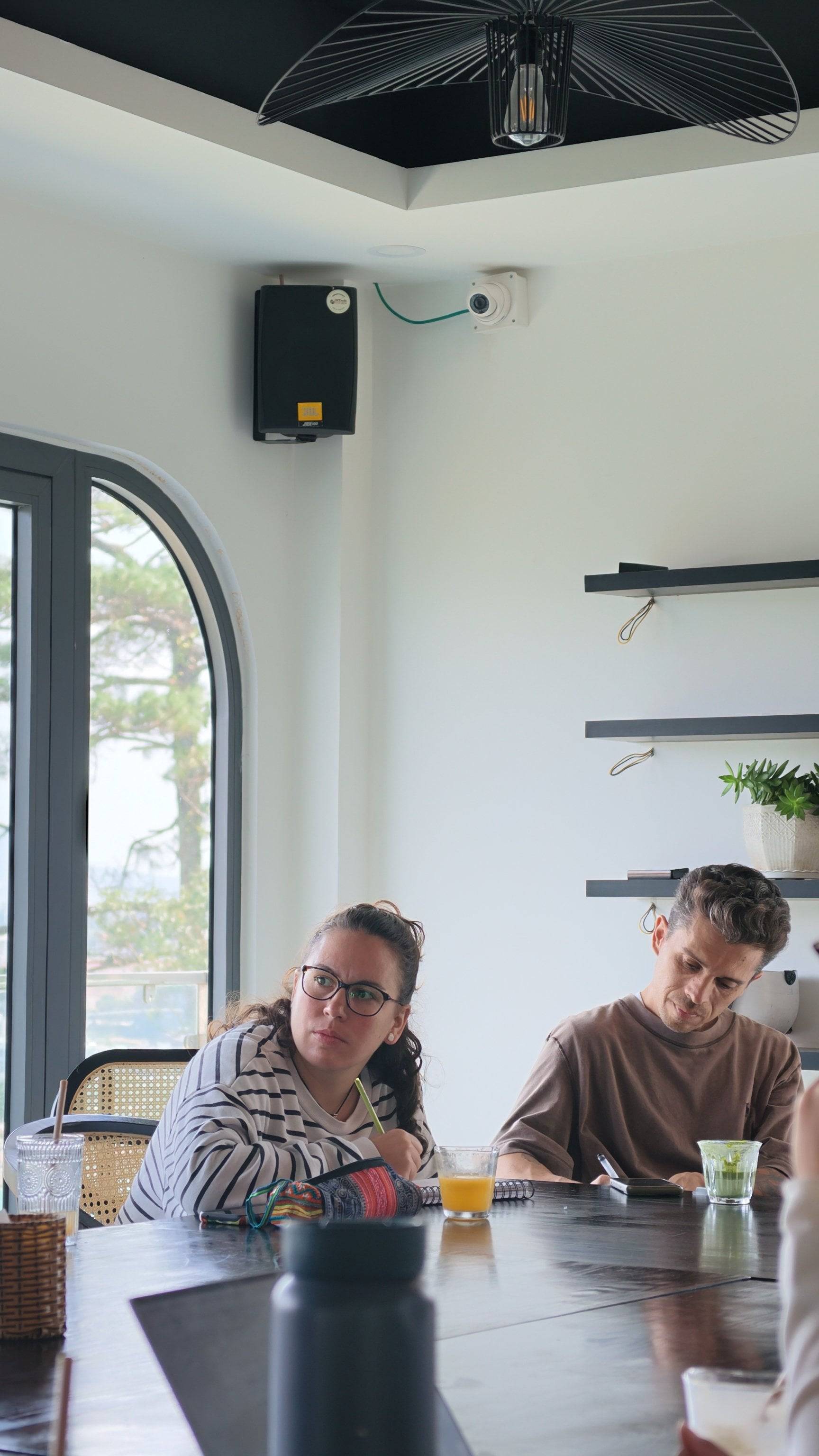 A group of individuals engaged in a meeting or discussion within a modern café setting in Đà Lạt, Vietnam.