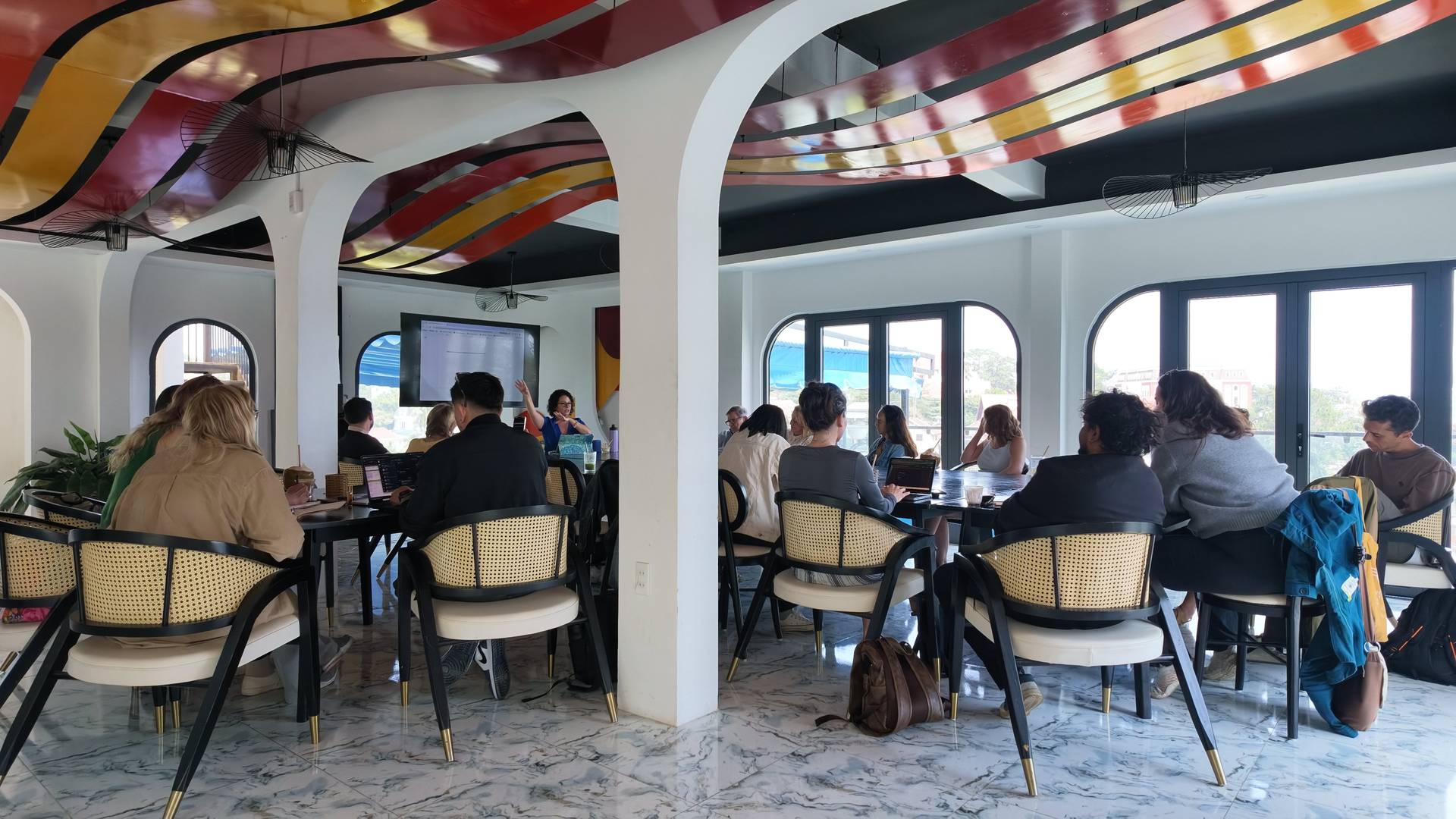 A vibrant meeting in a modern café in Đà Lạt, Vietnam, with attendees engaged in discussion and presentations.