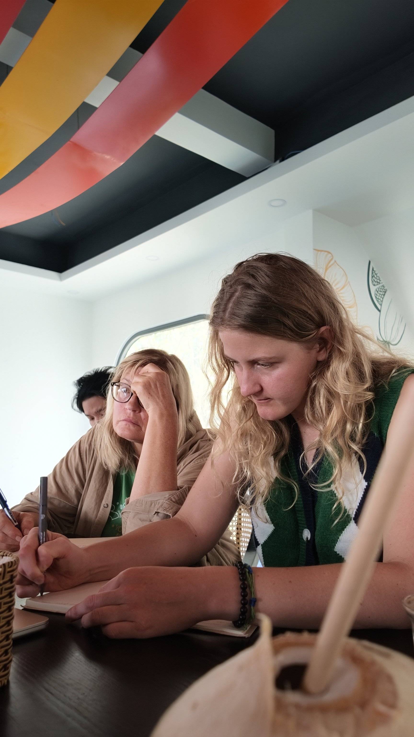 A group of individuals is engaged in a focused activity, possibly taking notes or working together, within a vibrant and modern setting in Đà Lạt, Vietnam.