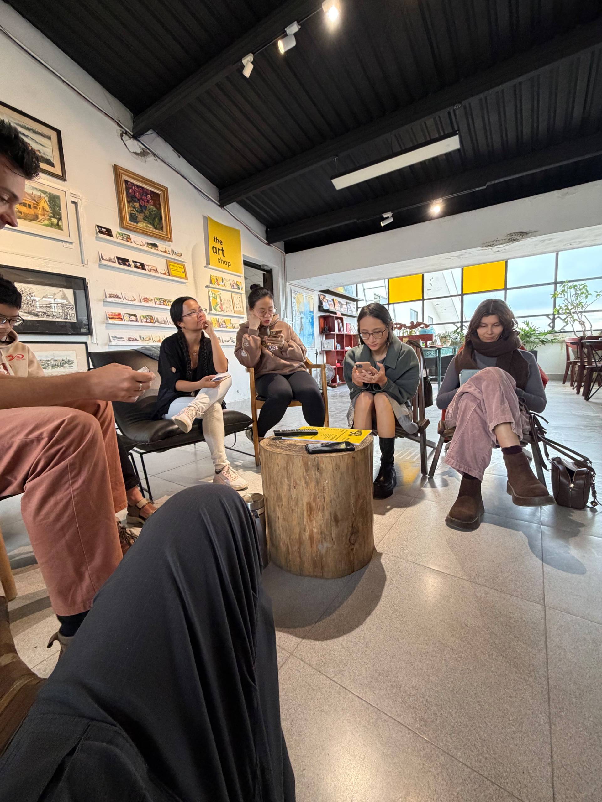 A community art event gathering in Đà Lạt's vibrant creative space, featuring group discussion and artistic collaboration among attendees.