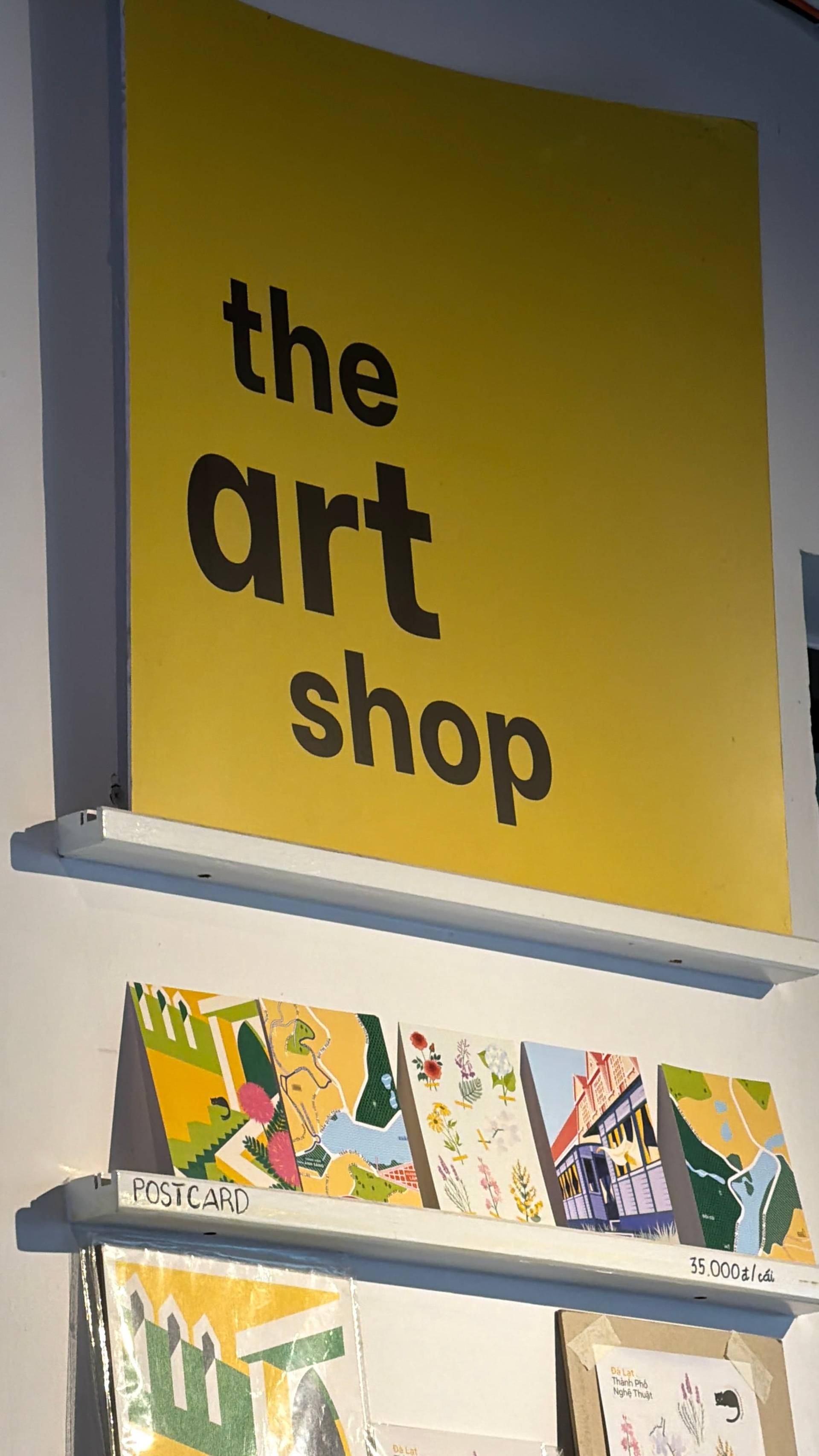 The Art Shop storefront in Đà Lạt featuring handcrafted postcards and local artwork, offering authentic Vietnamese souvenirs and artisanal goods.