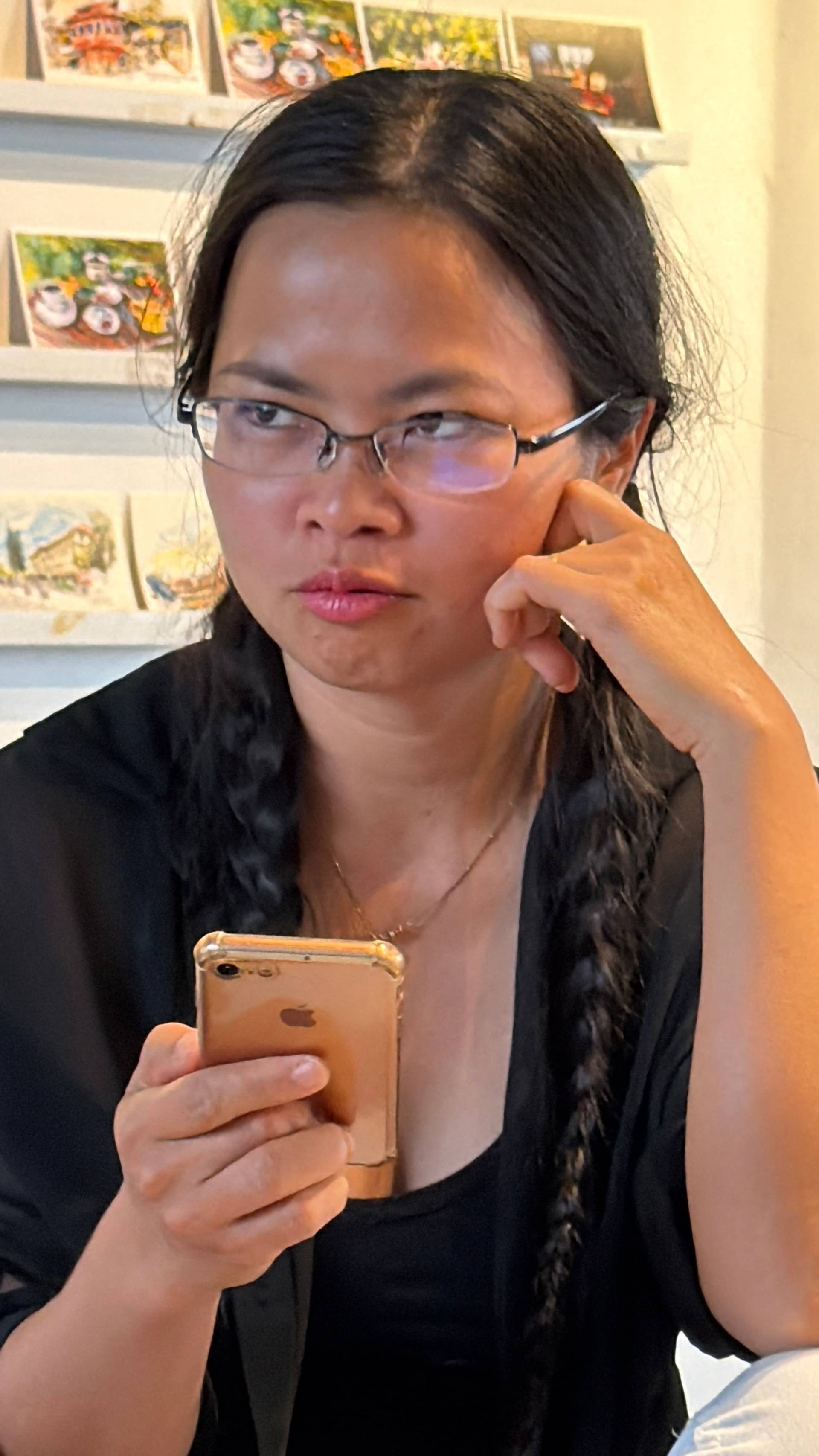 Thoughtful moment in an art gallery or creative studio space in Đà Lạt, showcasing curated artwork and photographs displayed on bright shelves.