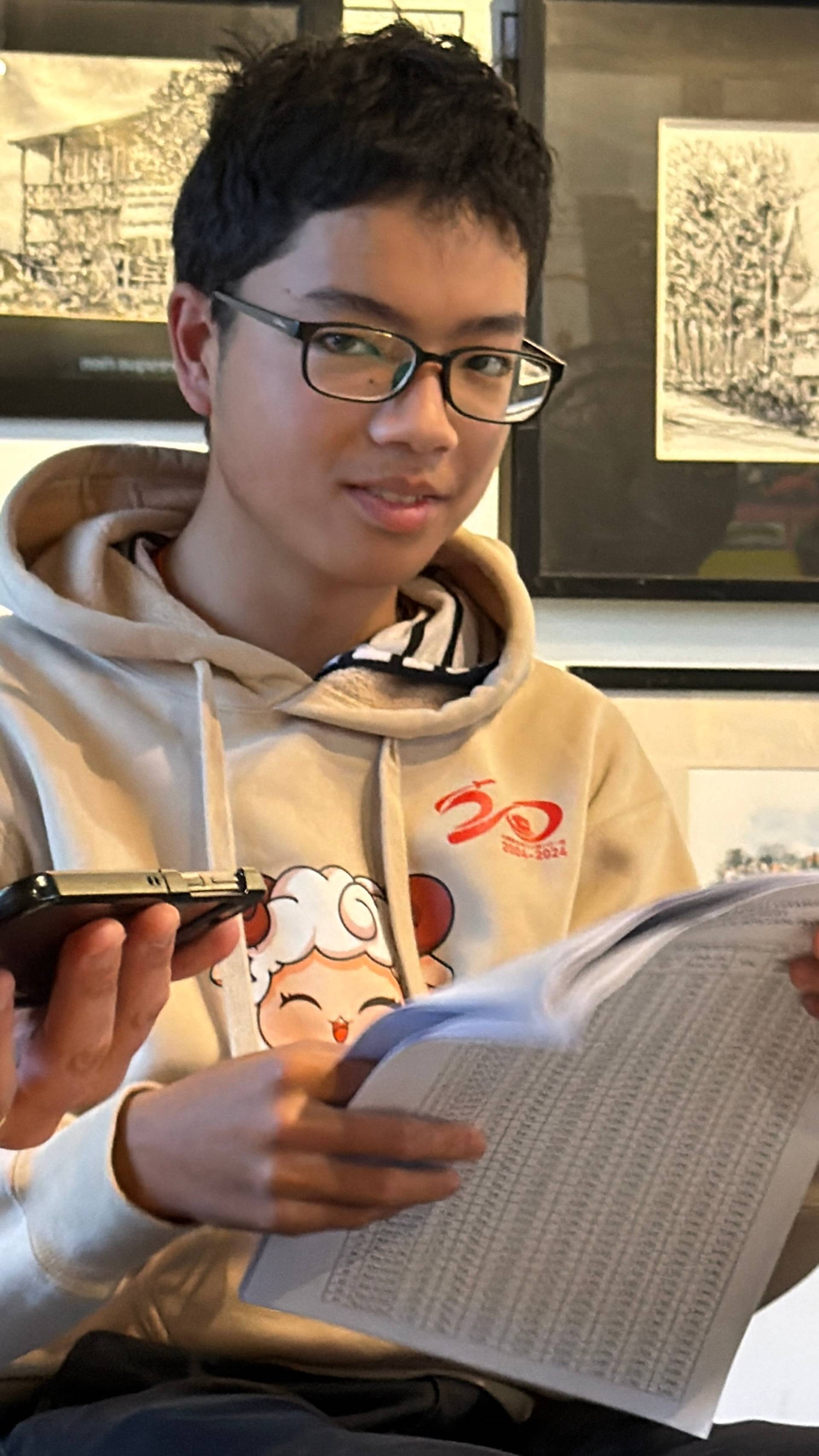 A contemplative moment in a Đà Lạt cultural space, where a visitor examines gallery materials amid displayed Vietnamese artworks and framed prints.